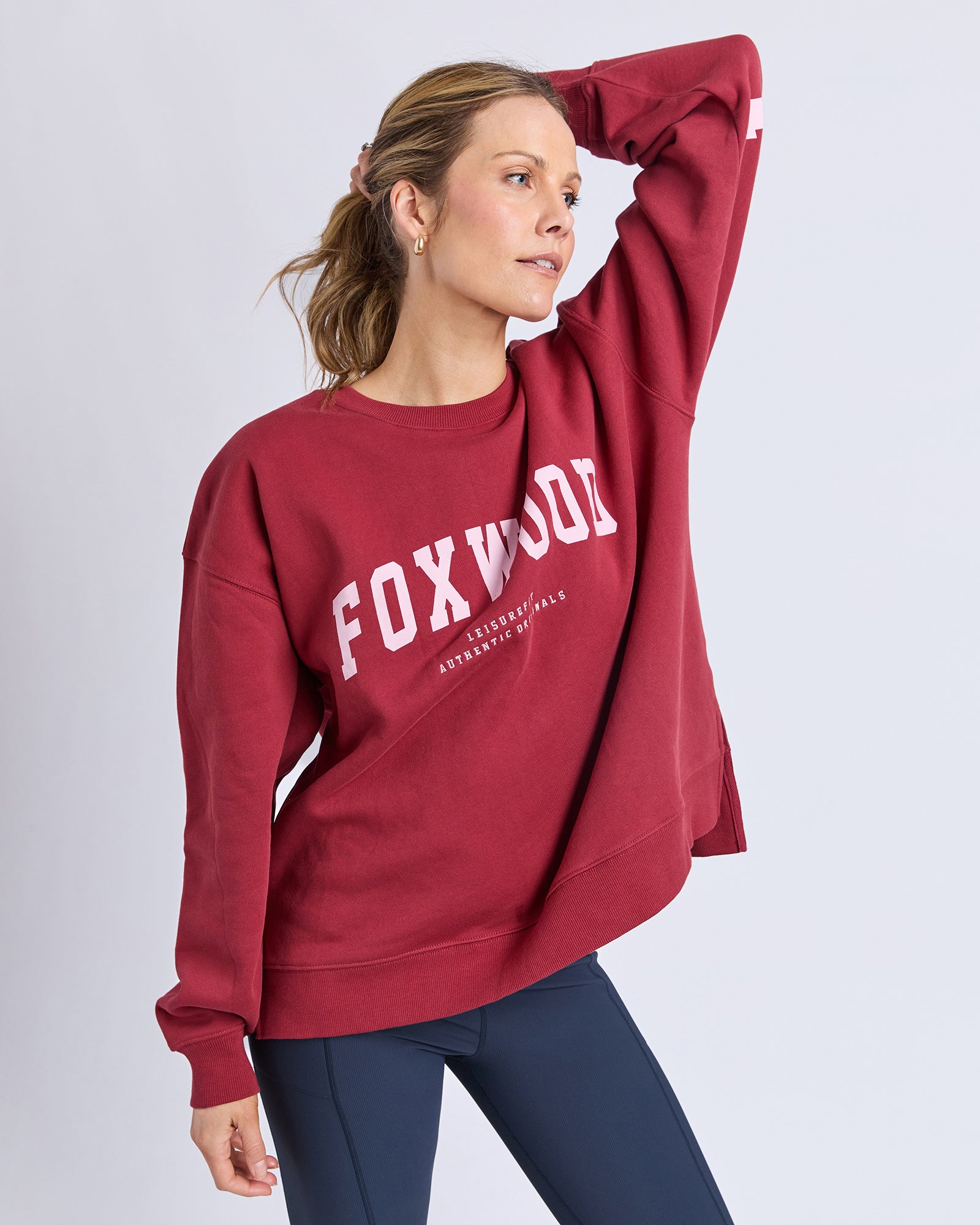 Woman wearing a red 'FOXWOOD' sweatshirt on a light gray background