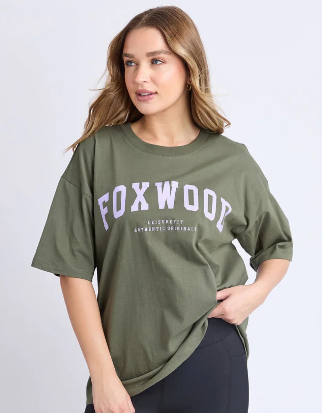 Image of Woman wearing a Foxwood green t-shirt with 'FOXWOOD' printed on it against a white background