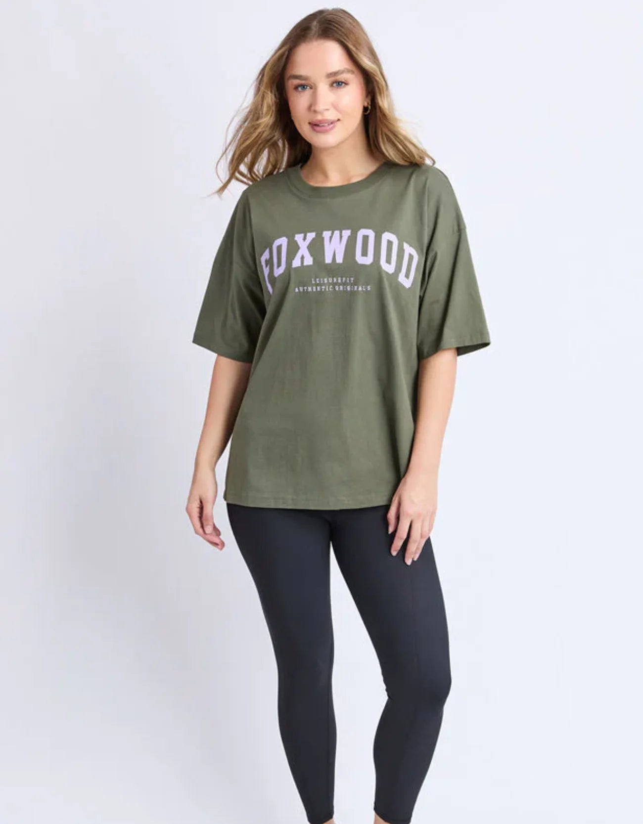 Woman wearing a Foxwood olive green t-shirt with 'FOXWOOD' printed on it against a white background