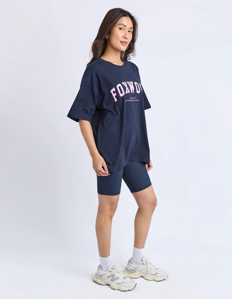 Woman wearing a Foxwood navy oversized t-shirt and shorts with 'FOX' branding on a white background