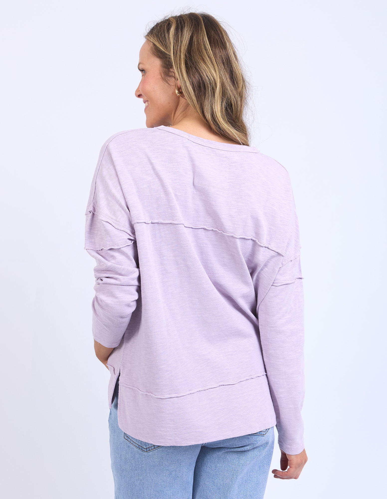 Back view of a Woman wearing a light purple lavender long sleeve tee on a white background