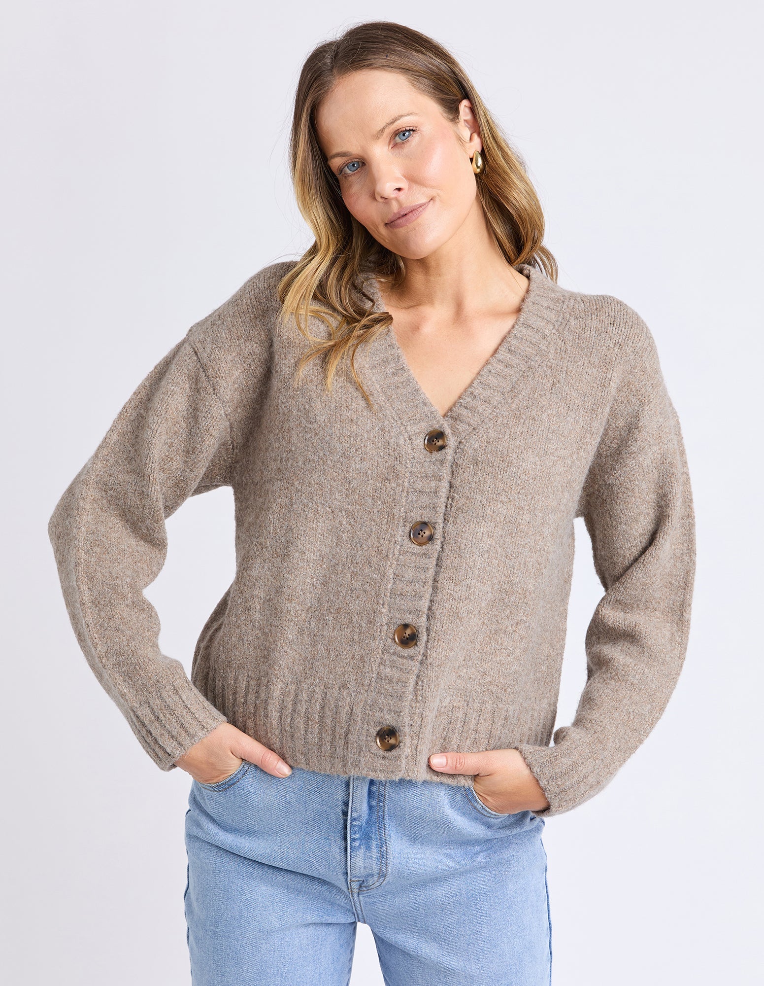 Image of Woman wearing a beige cardigan with buttons on a light gray background