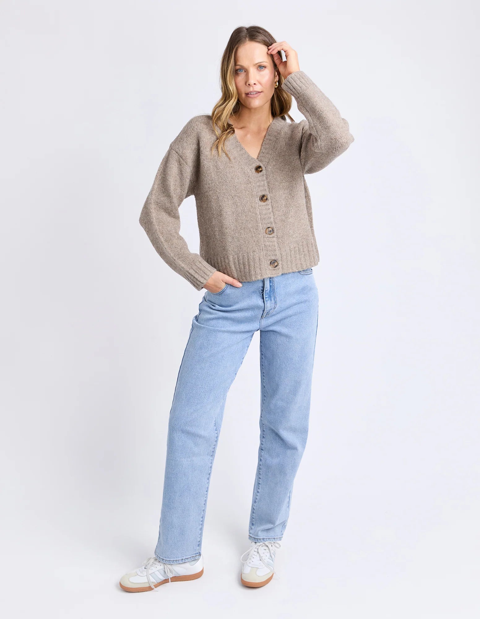 Woman wearing a Foxwood beige cardigan and light blue jeans on a white background
