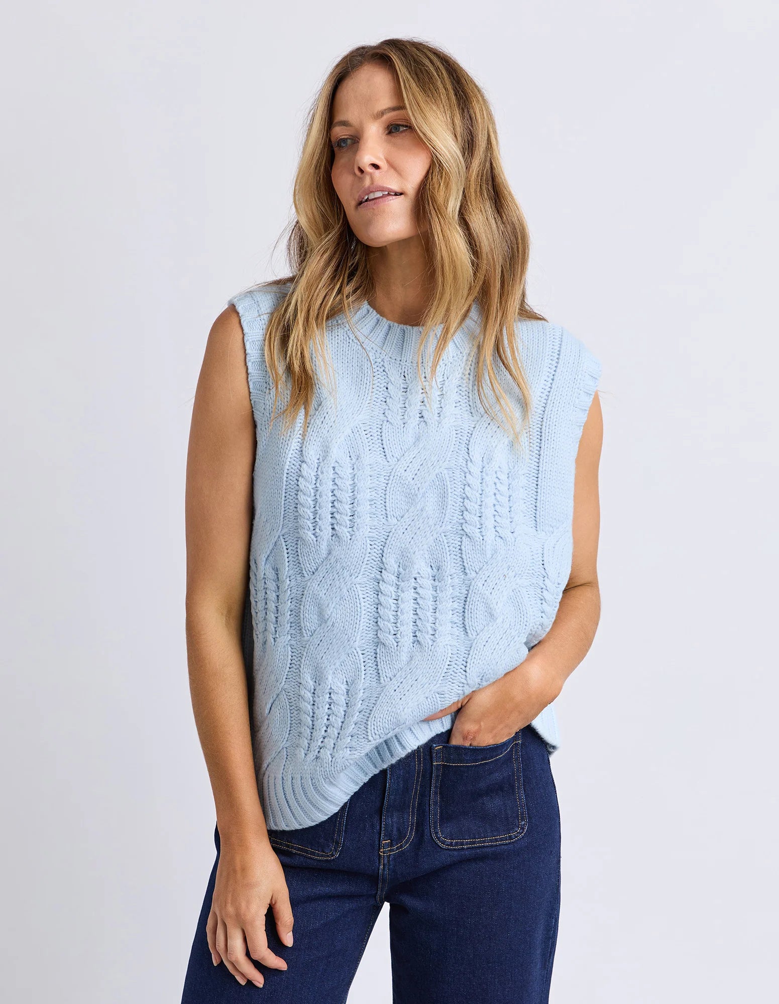 Image of Woman wearing a Foxwood light blue sleeveless knitted top against a white background