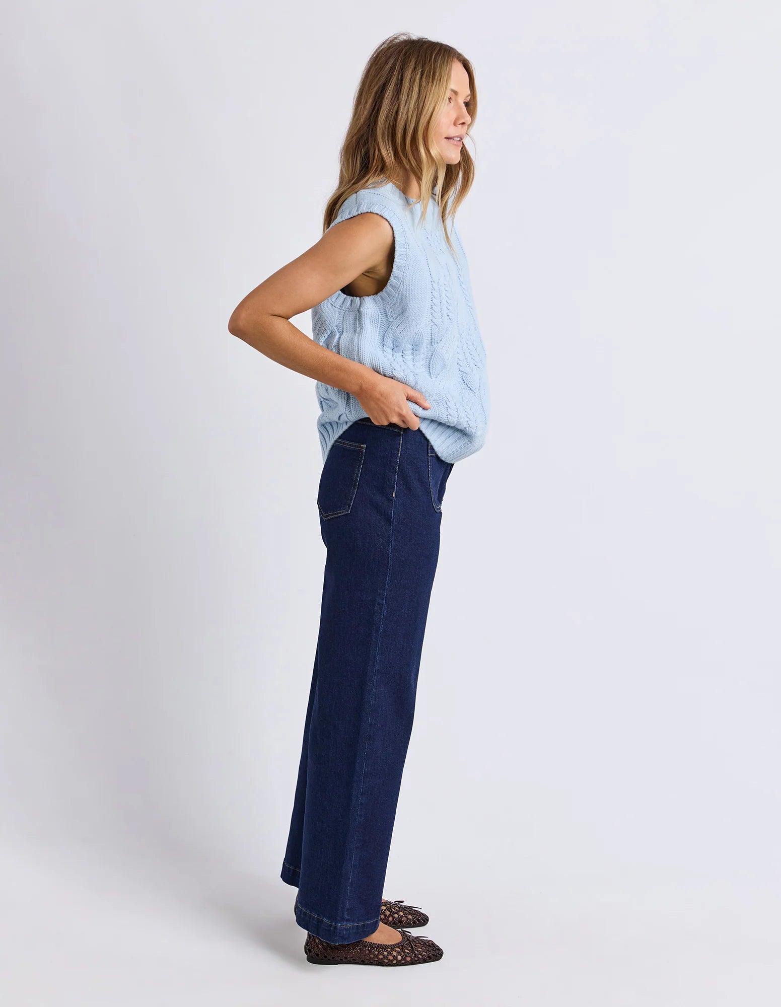 Image of Woman wearing a Foxwood light blue sleeveless top and dark blue pants on a white background