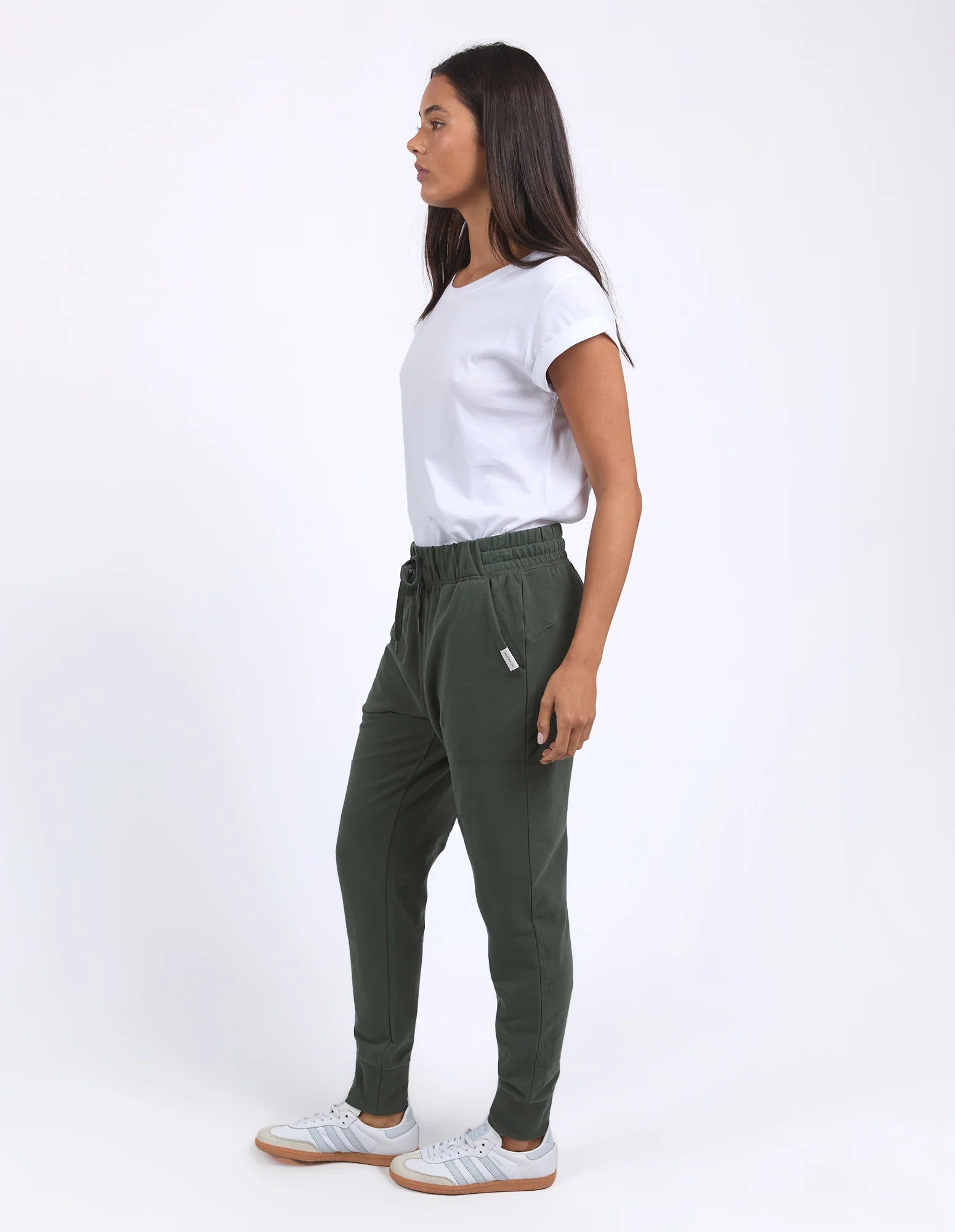 Image of Woman wearing a white t-shirt and Foxwood green pants on a white background