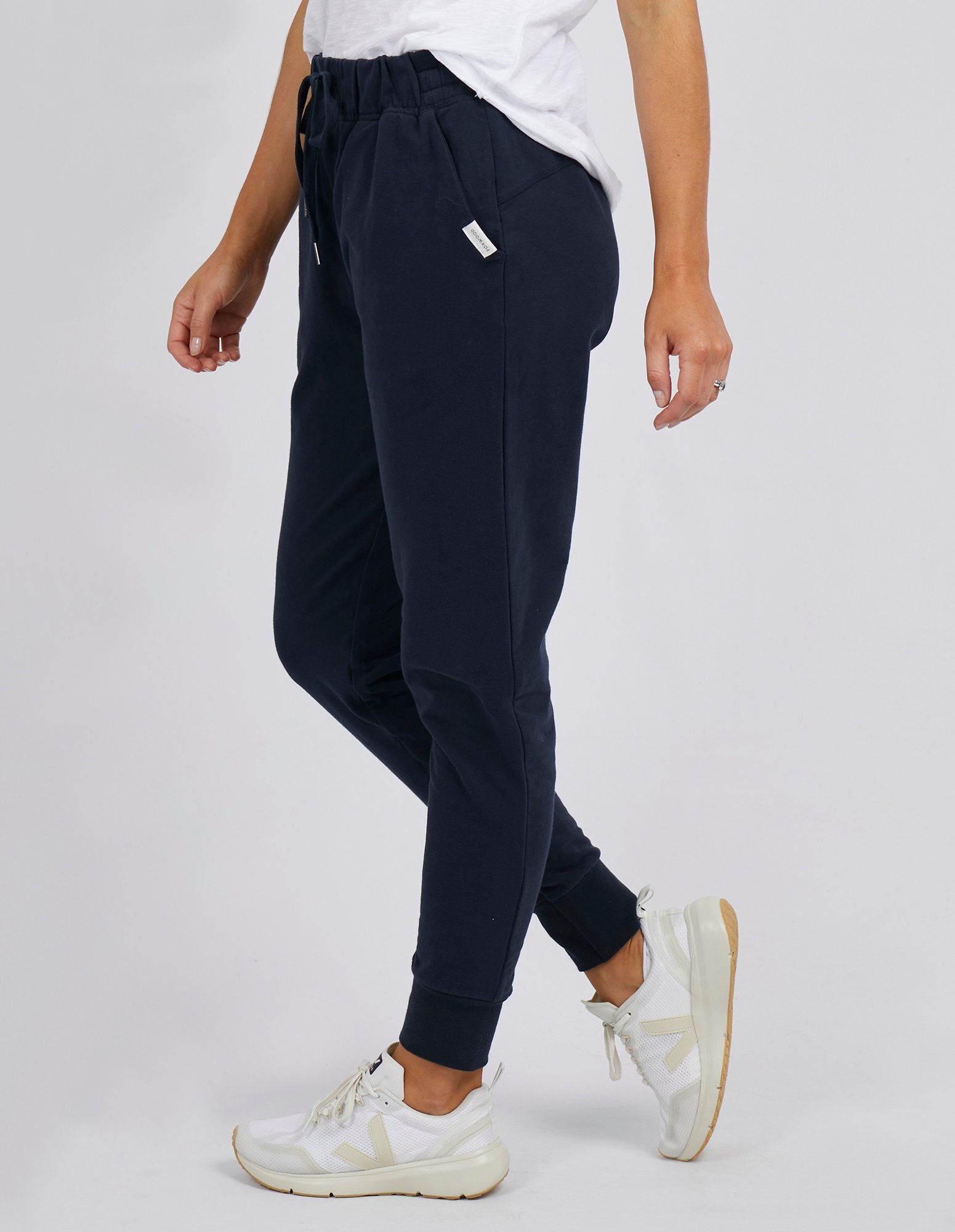 Image of Woman wearing Foxwood lazy day trackpants in navy paired with a white singlet on a white background