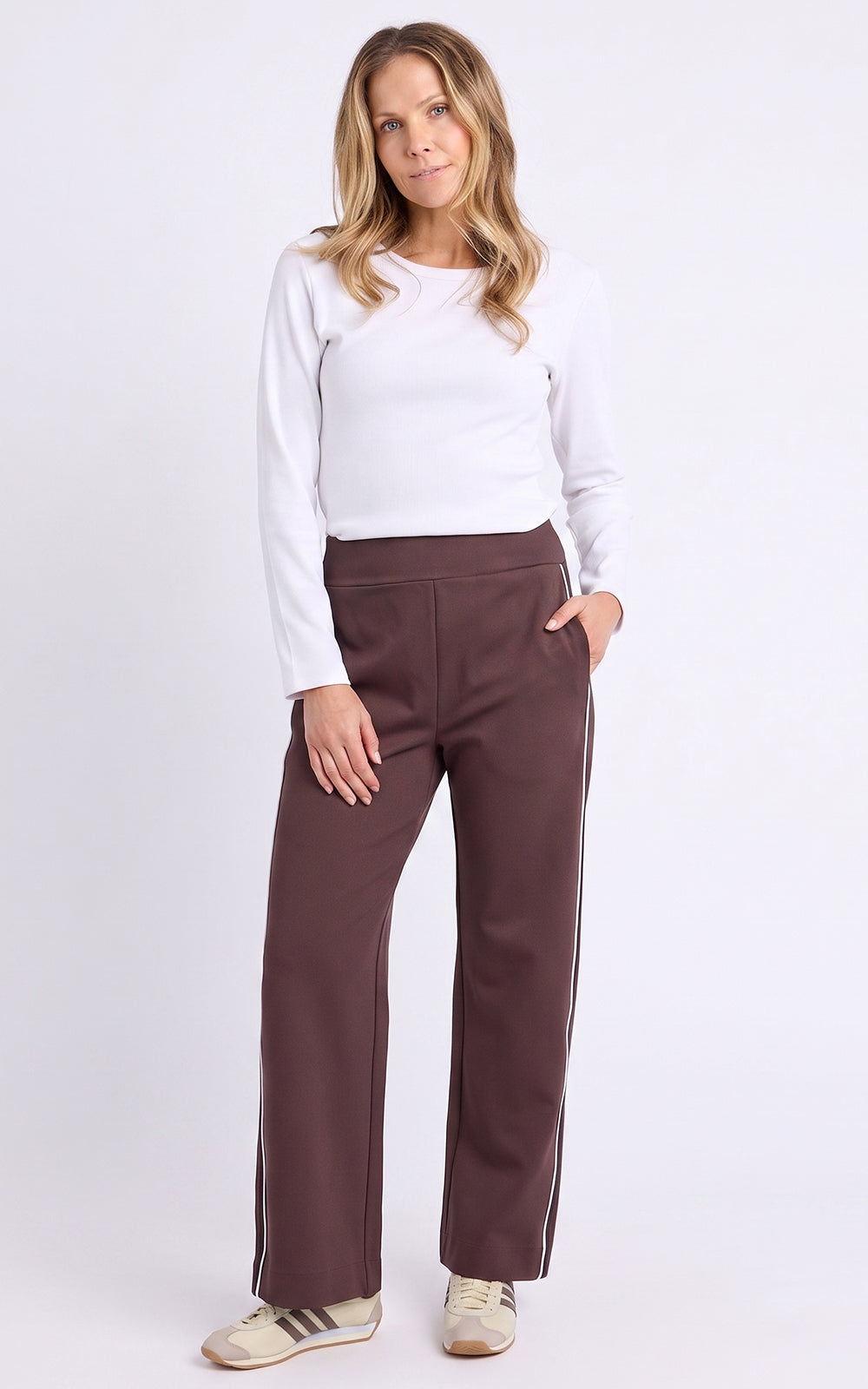 Image of Woman wearing a white top and Foxwood brown pants on a white background
