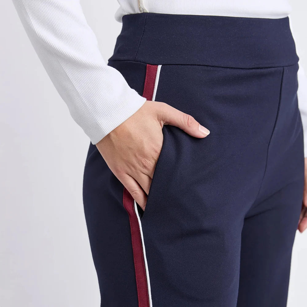 Image of Woman wearing Foxwood navy pants and a white shirt on a light gray background