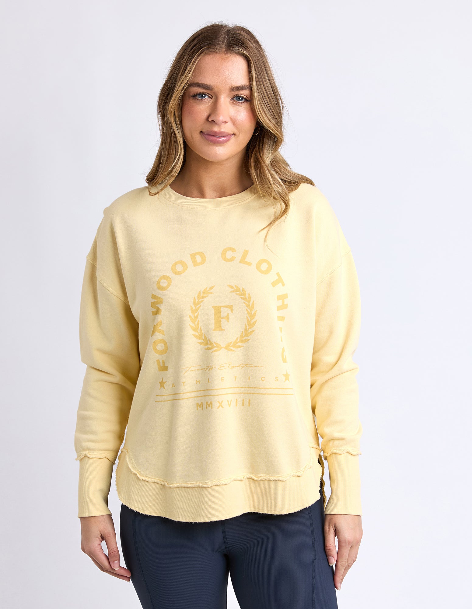 Collection of Woman wearing a Foxwood light yellow sweatshirt with a logo on a white background in a gallery layout