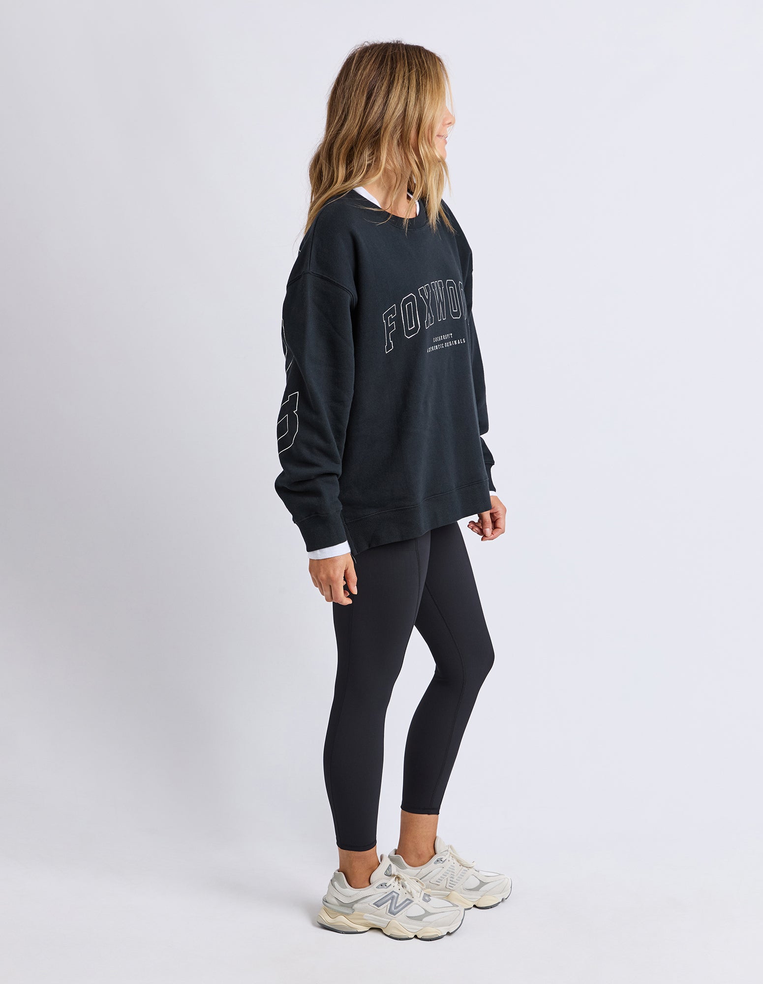 Woman wearing a black sweatshirt and leggings on a white background