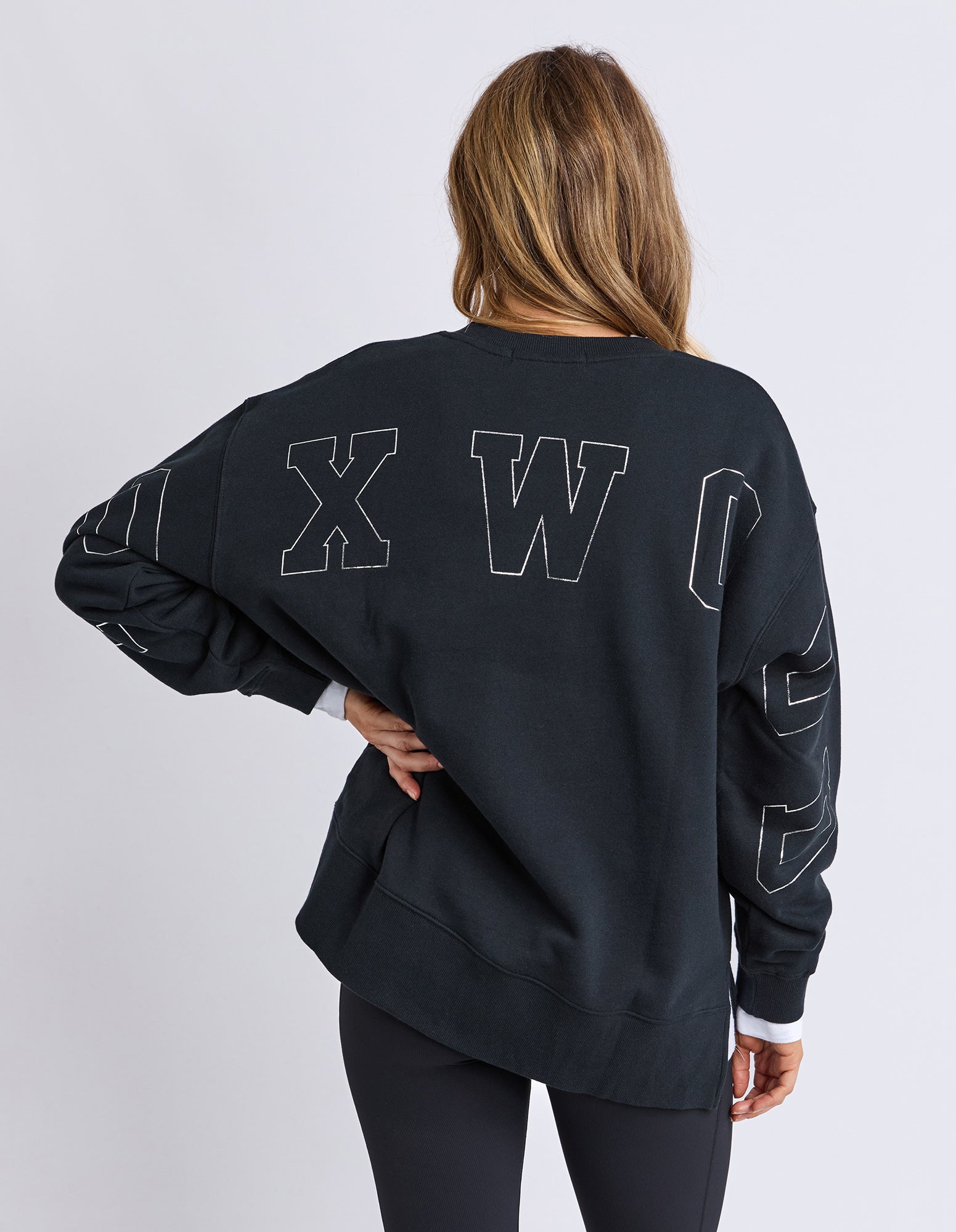 Image of Woman wearing a Foxwood black sweatshirt on the back against a white background