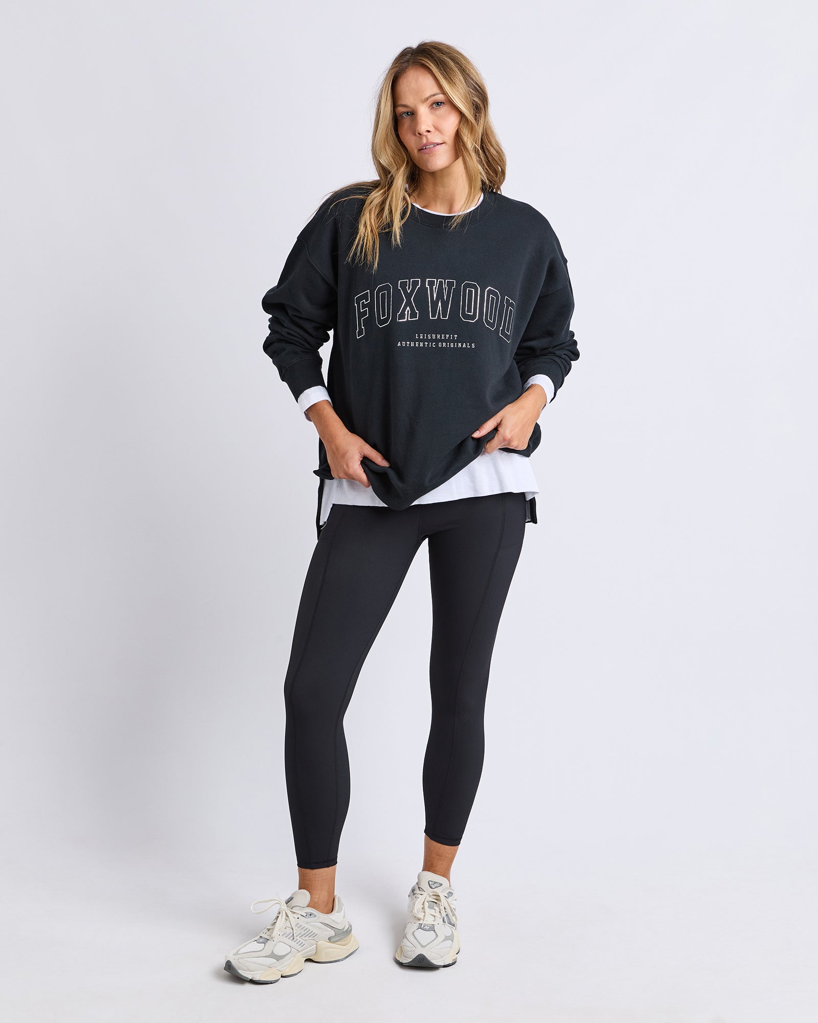 Image of Woman wearing interval crew with black leggings on a white background