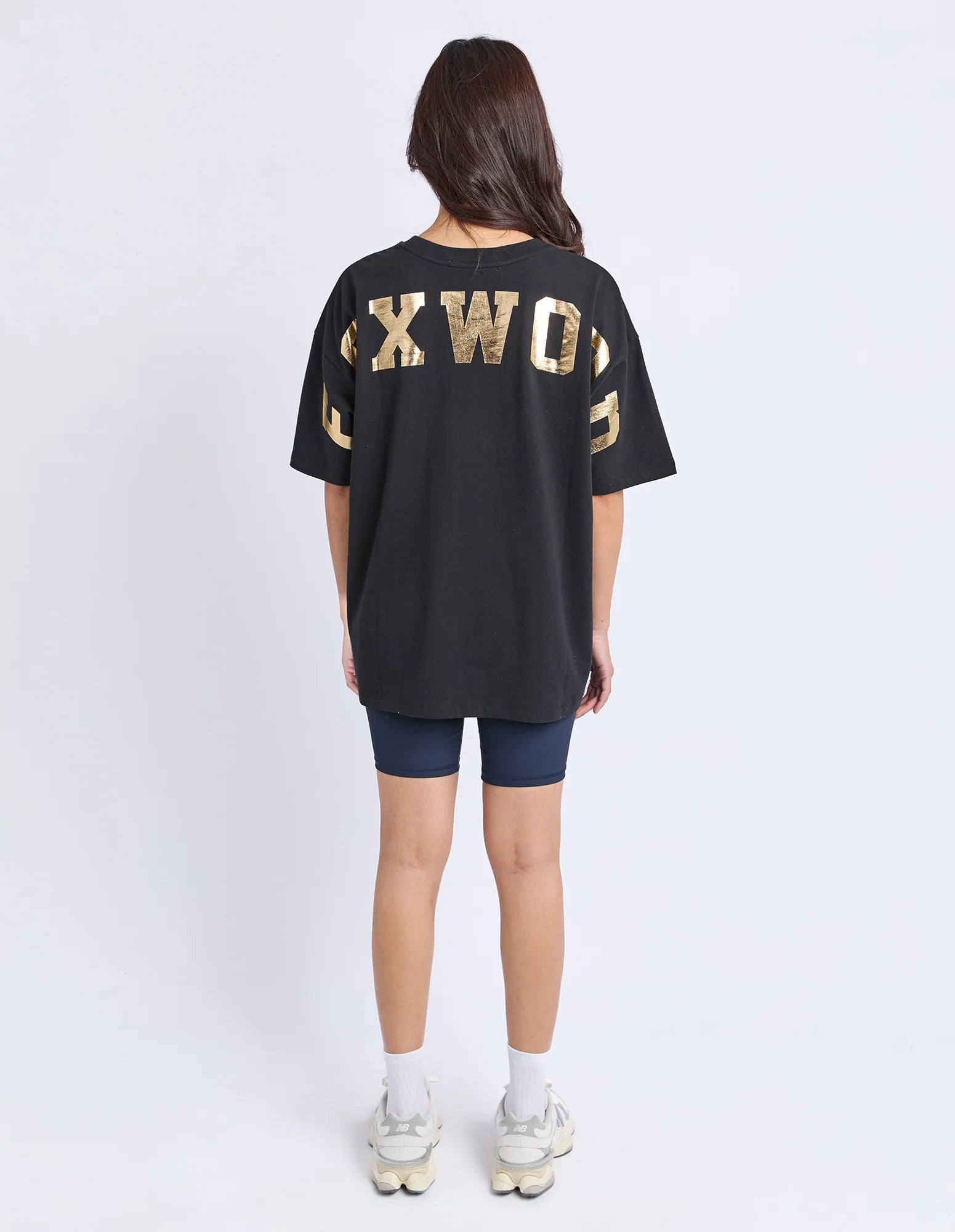 Image of Woman wearing a black t-shirt with gold text on a white background