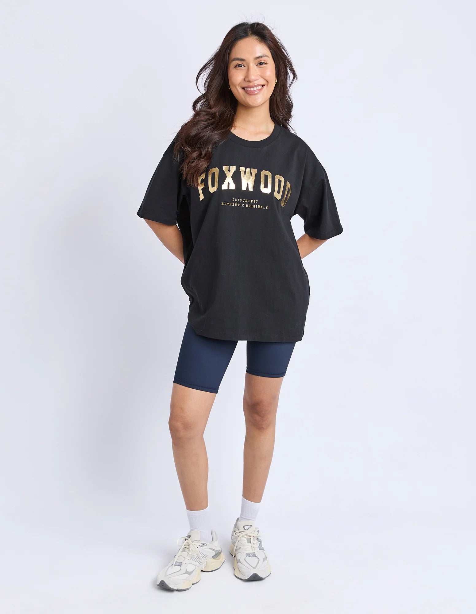 Woman wearing a black t-shirt with 'FOXWOOD' printed on it against a white background
