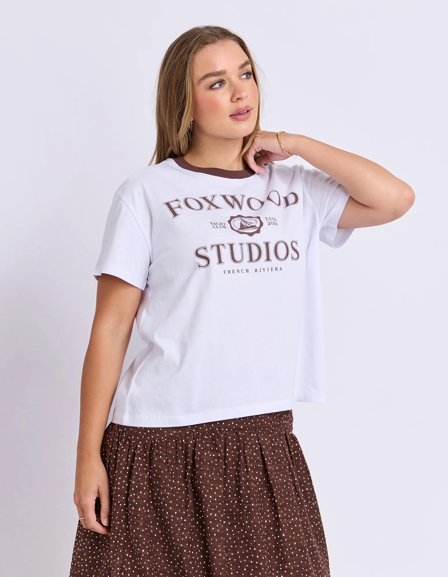 Image of Woman wearing a white t-shirt with 'Foxwood Studios' text and logo on a plain background
