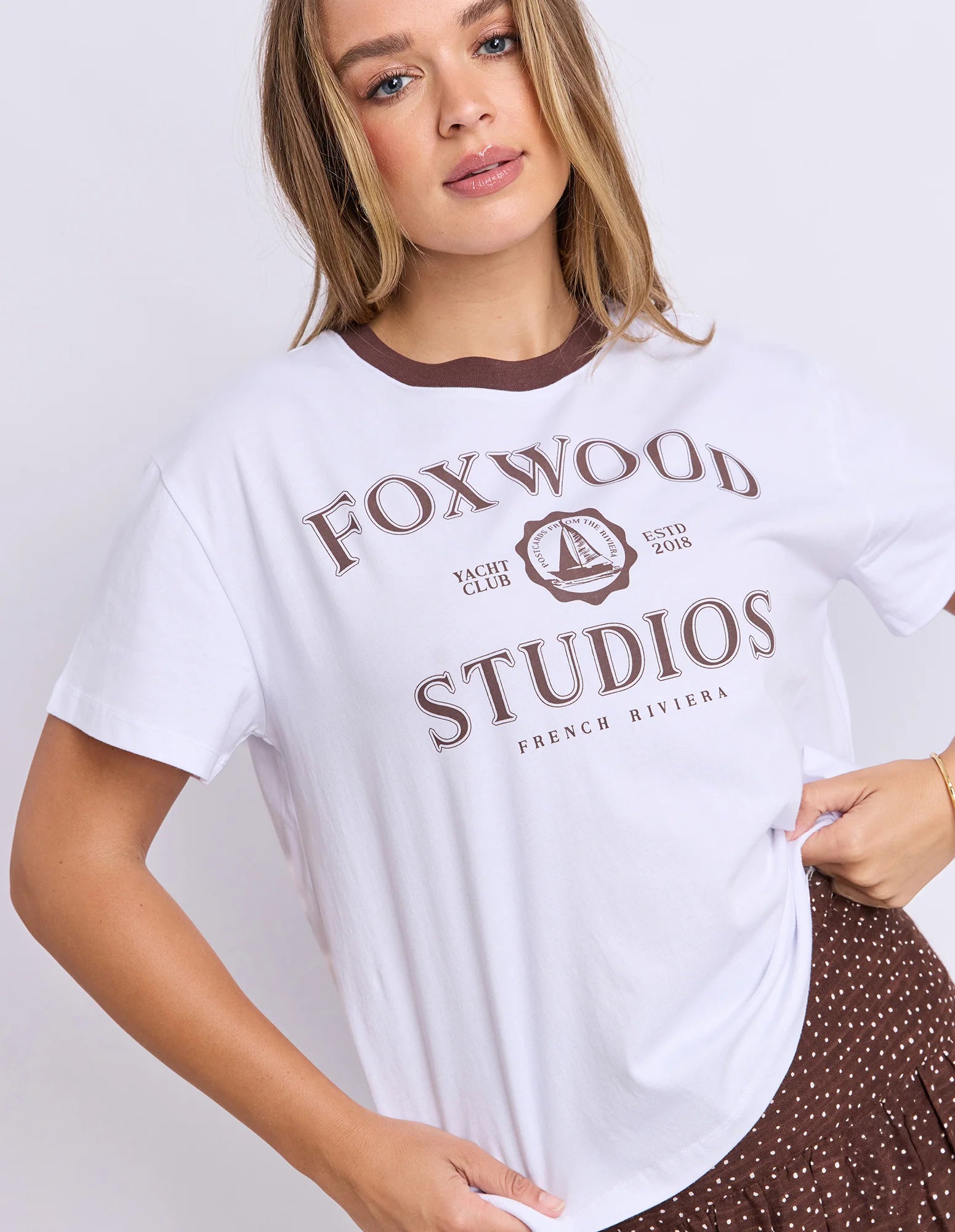 Image of Woman wearing a Foxwood white t-shirt with 'Foxwood Studios' text and logo on a plain background