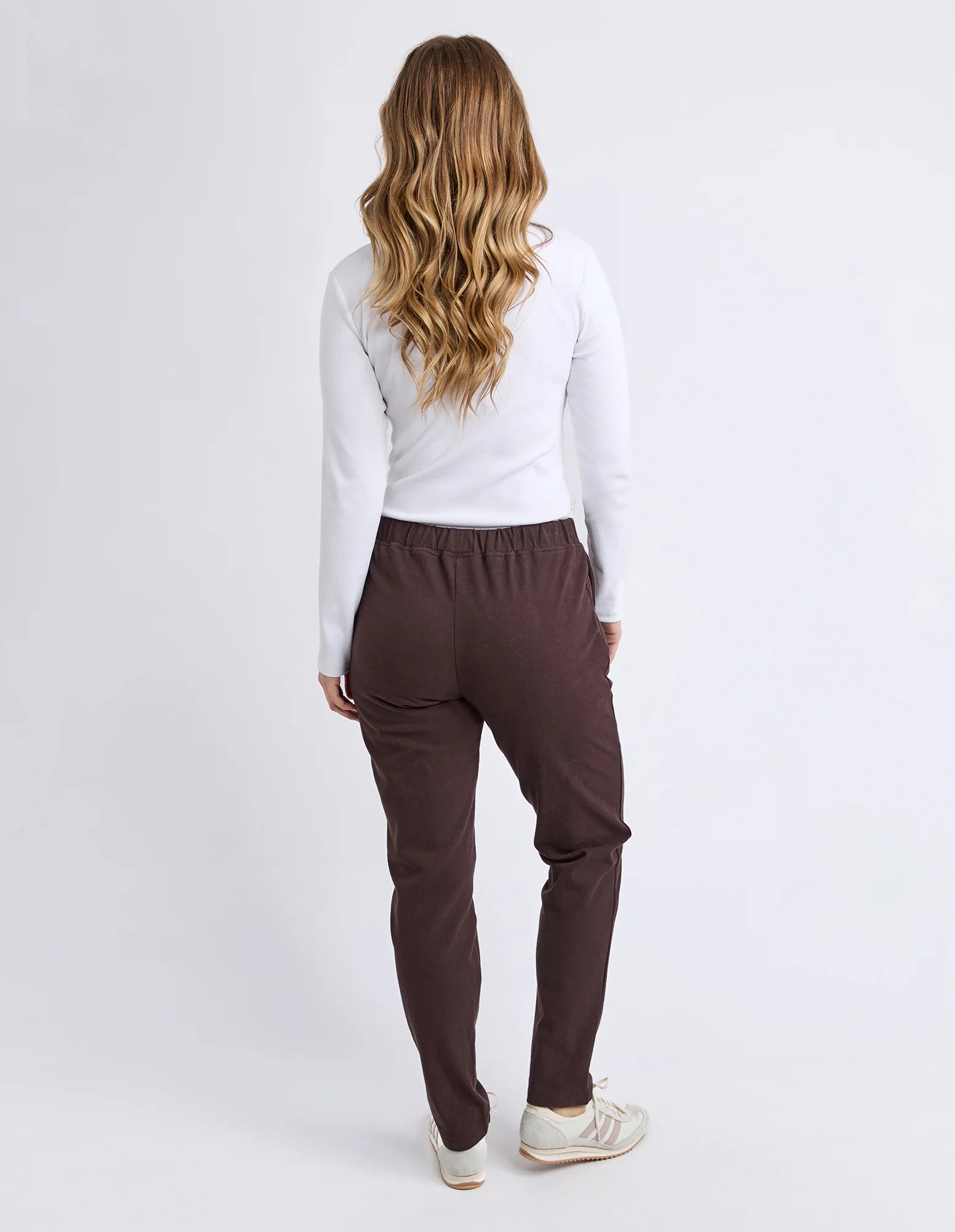 Image of Person wearing Foxwood brown pants and a white top on a white background