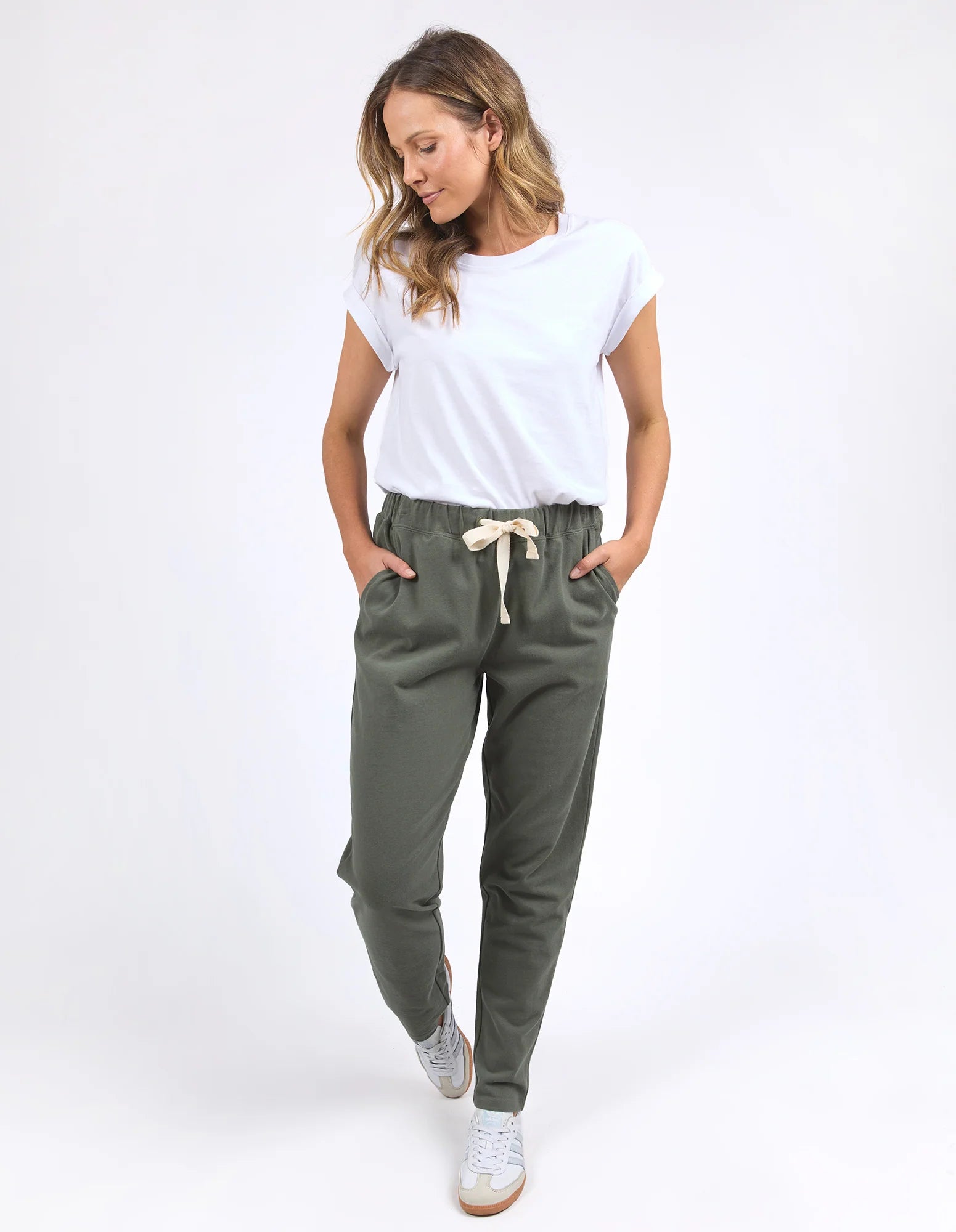Image of Woman wearing Foxwood khaki trackpants with a white tshirt on a plain background