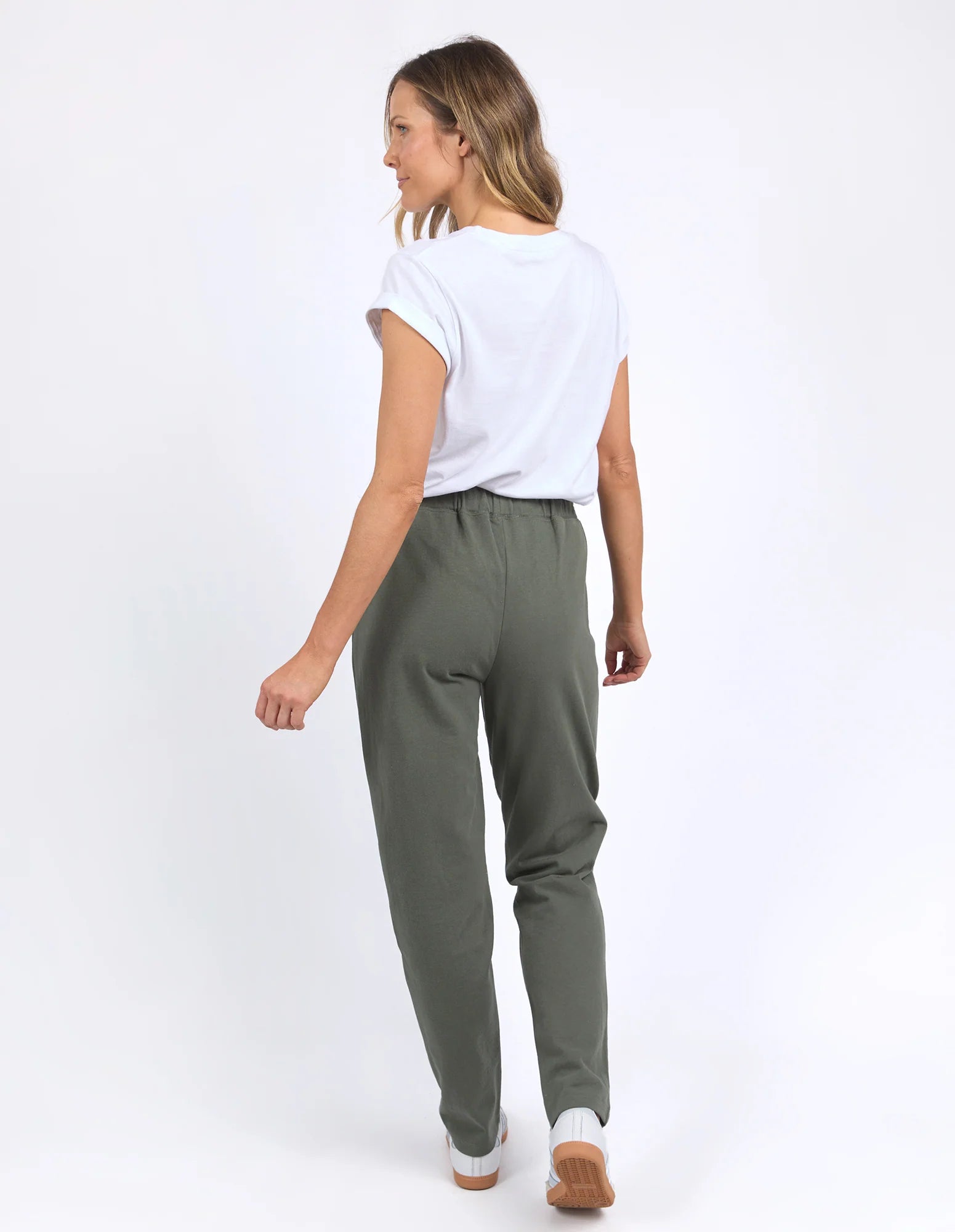 Image of Woman wearing Foxwood khaki trackpants with a white tshirt on a plain background
