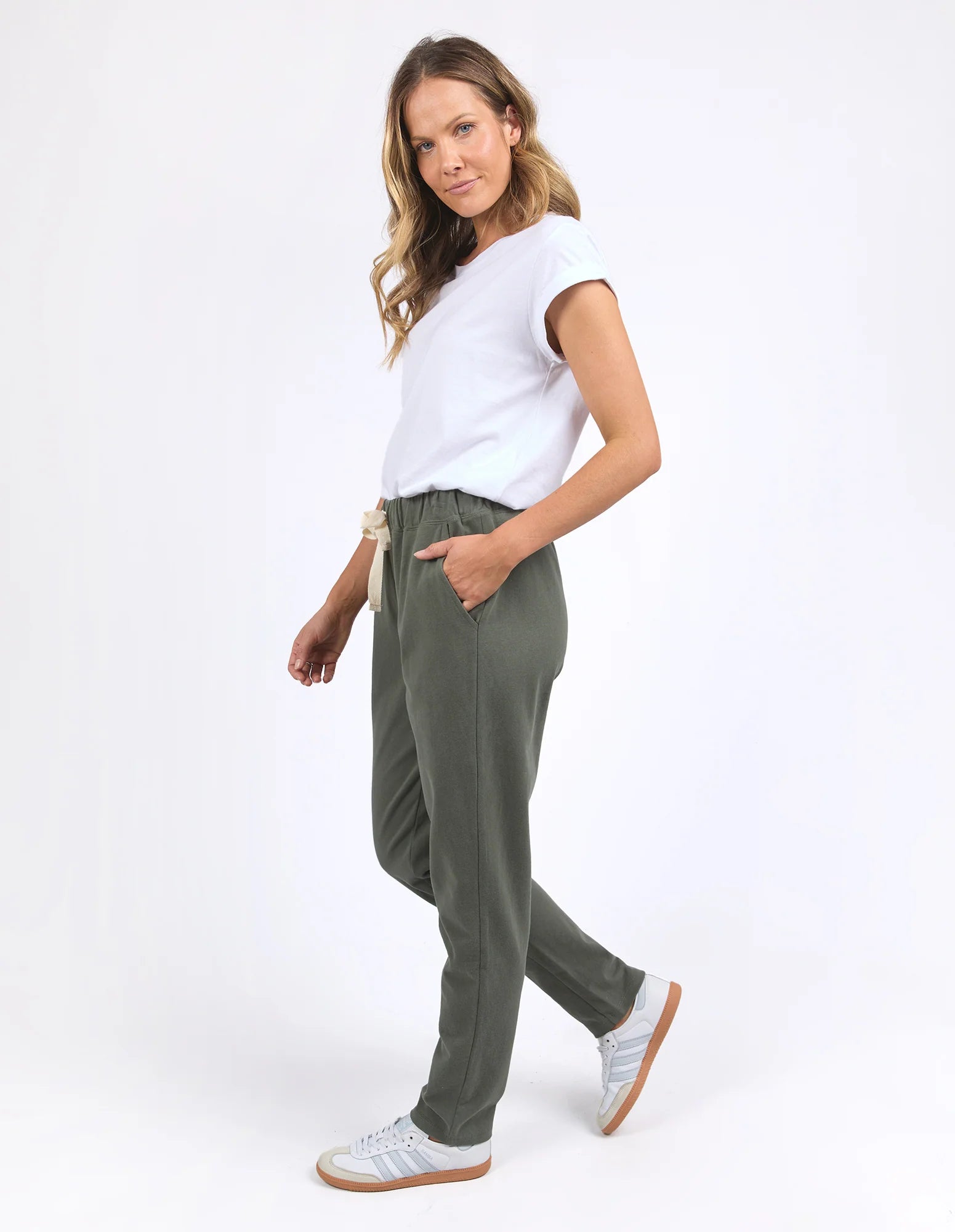 Image of Woman wearing Foxwood khaki trackpants with a white tshirt on a plain background