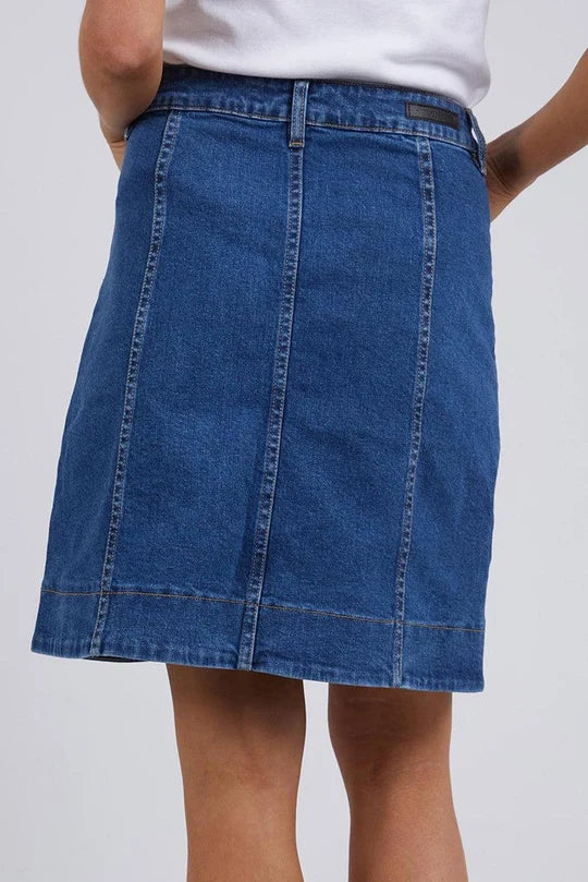 Image of Foxwood blue denim A-line skirt worn by a woman, shown from the waist down against a light gray studio background.