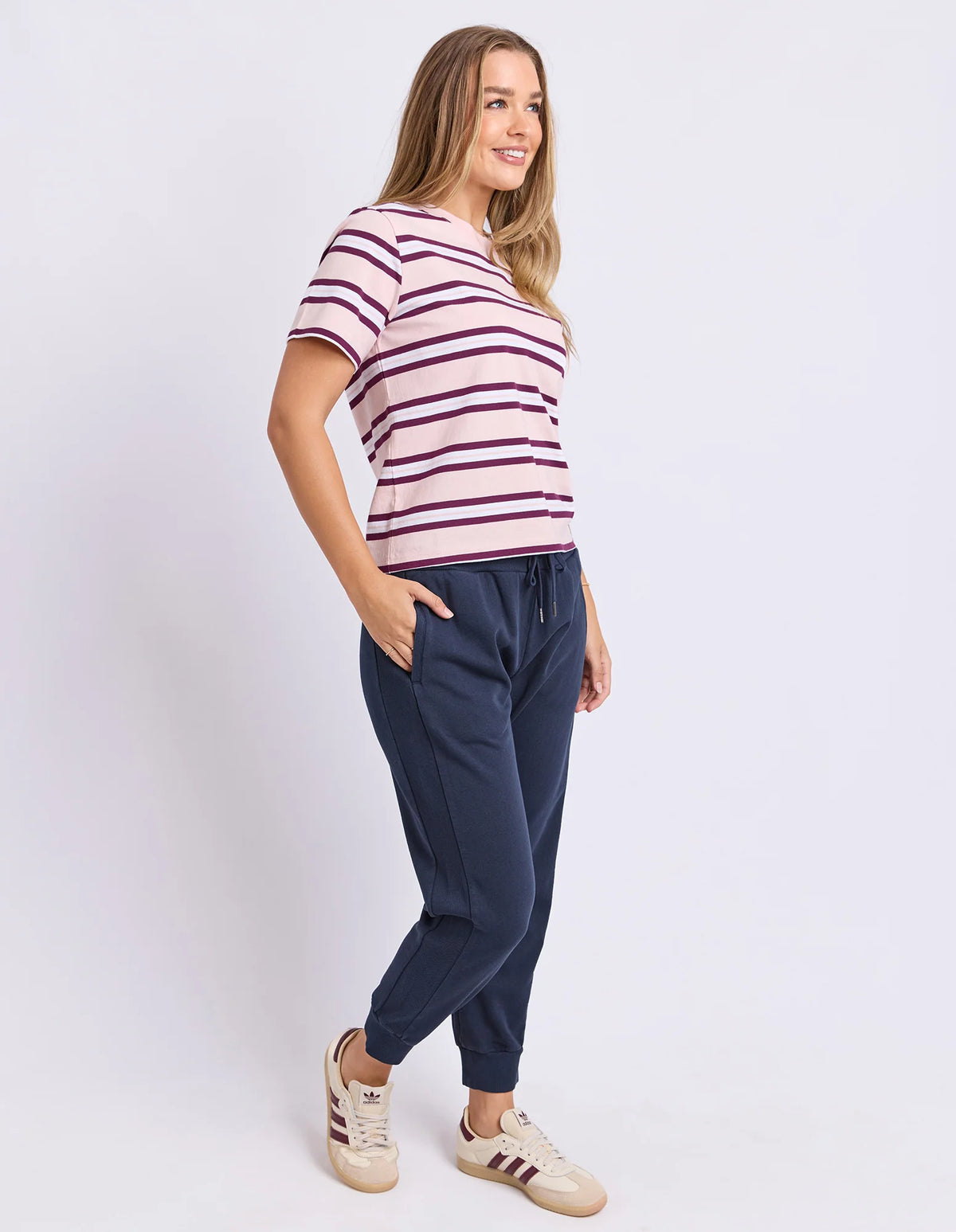 Woman wearing a Foxwood striped shirt and navy jogger pants on a white background