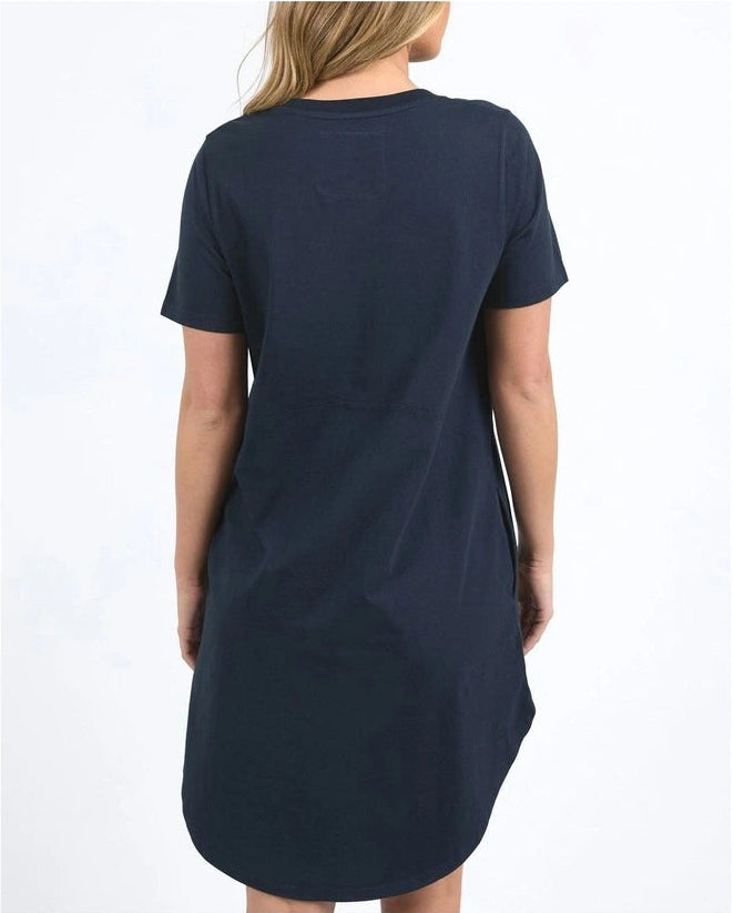 Image of A woman viewed from the back wearing a Foxwood dark navy blue short-sleeve t-shirt dress against a plain white background.