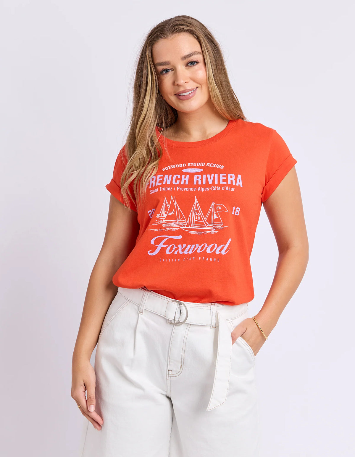Woman wearing Foxwood red graphic tshirt paired with white denim jeans on a plain background