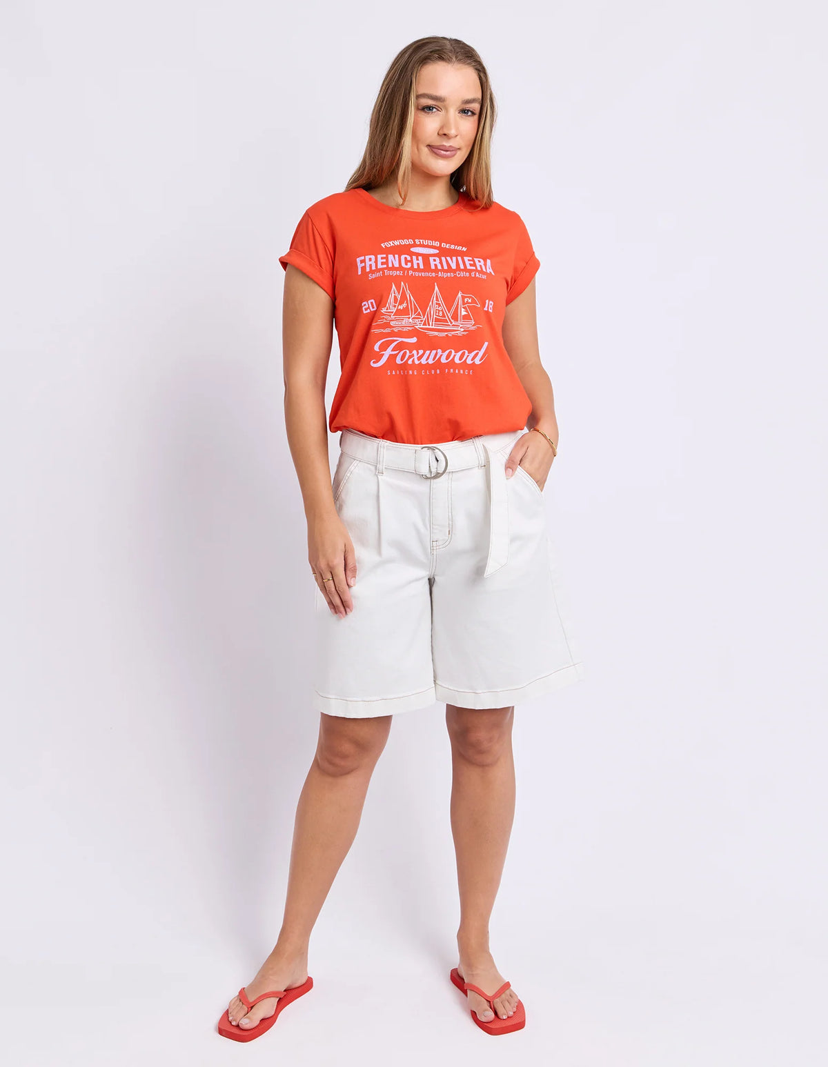 Woman wearing Foxwood red graphic tshirt paired with white denim jeans on a plain background