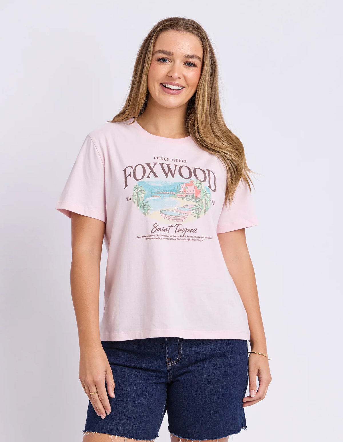 Woman wearing Foxwood pink graphic tshirt paired with denim jeans on a plain background