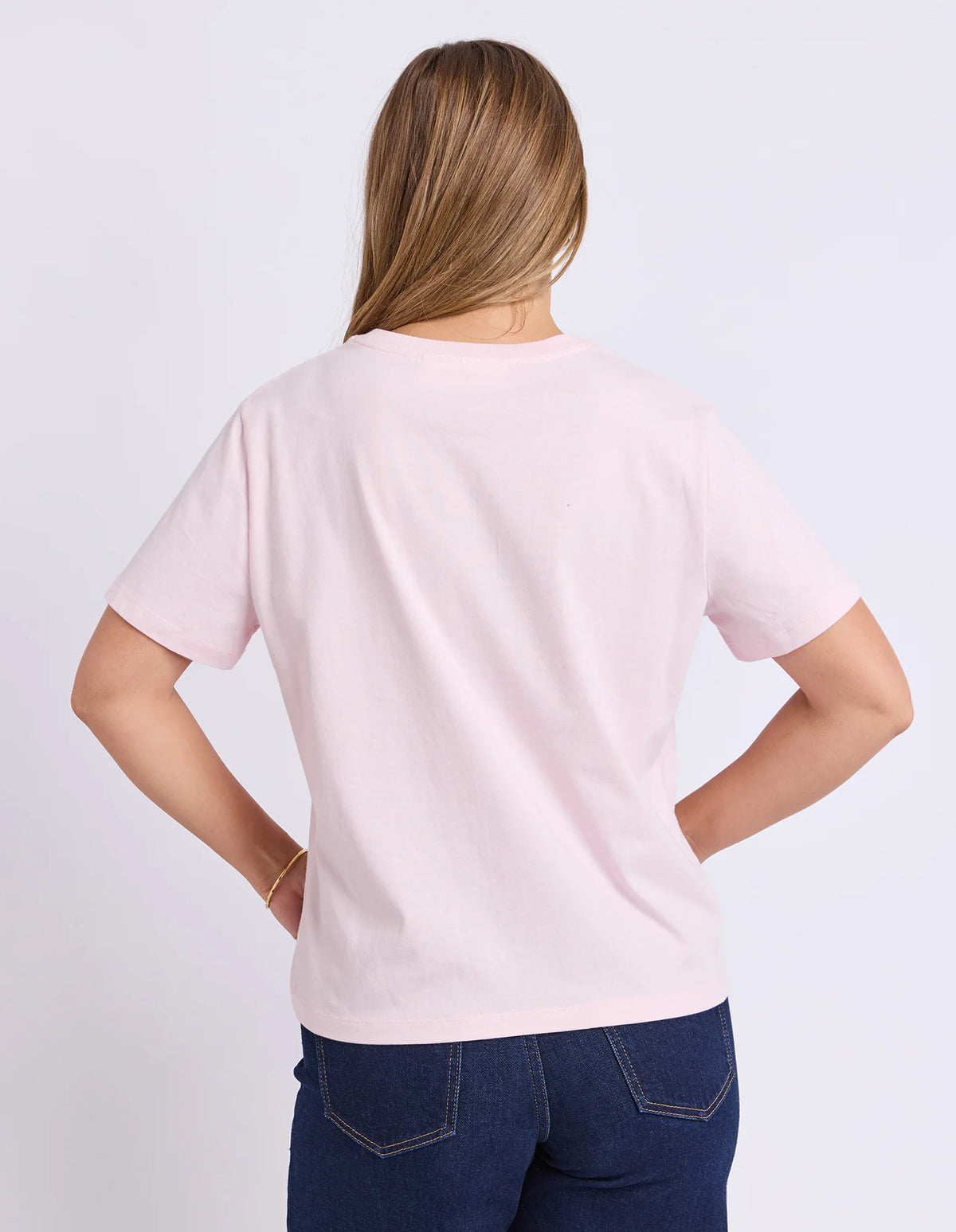 Woman wearing Foxwood pink graphic tshirt paired with denim jeans on a plain background
