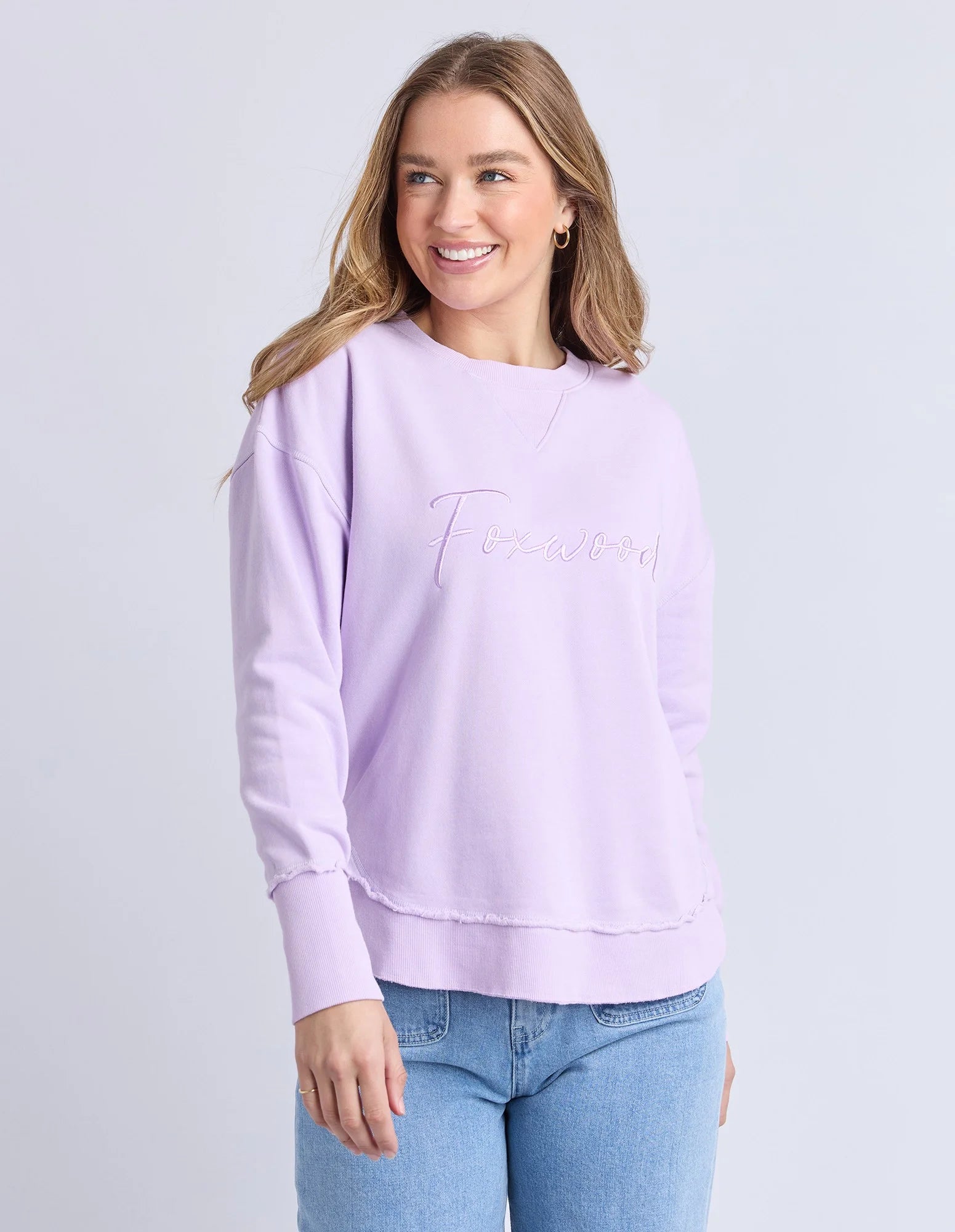Woman wearing a Foxwood light purple jumper with text on a plain background
