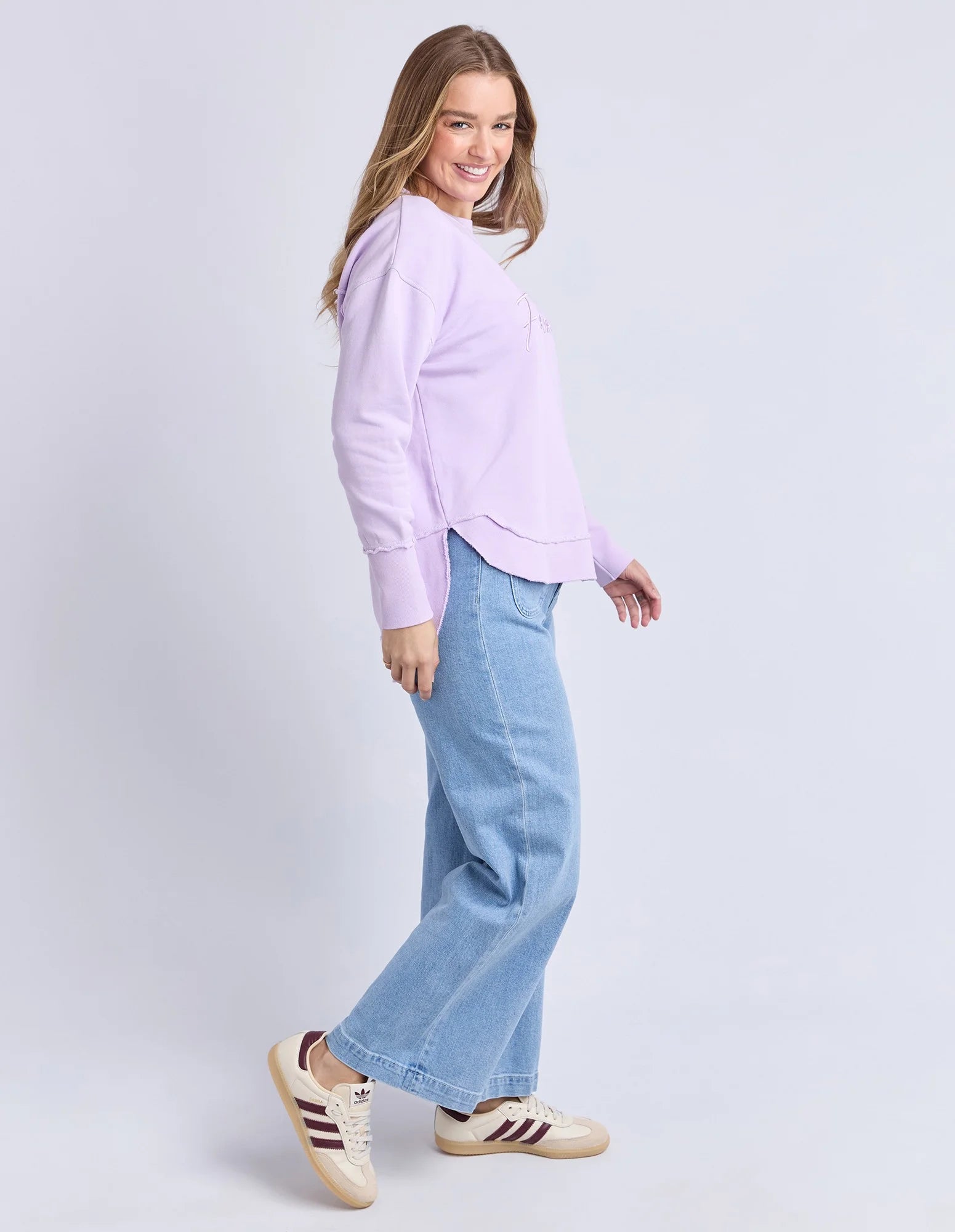 Image of Woman wearing a Foxwood light purple shirt and blue jeans on a white background