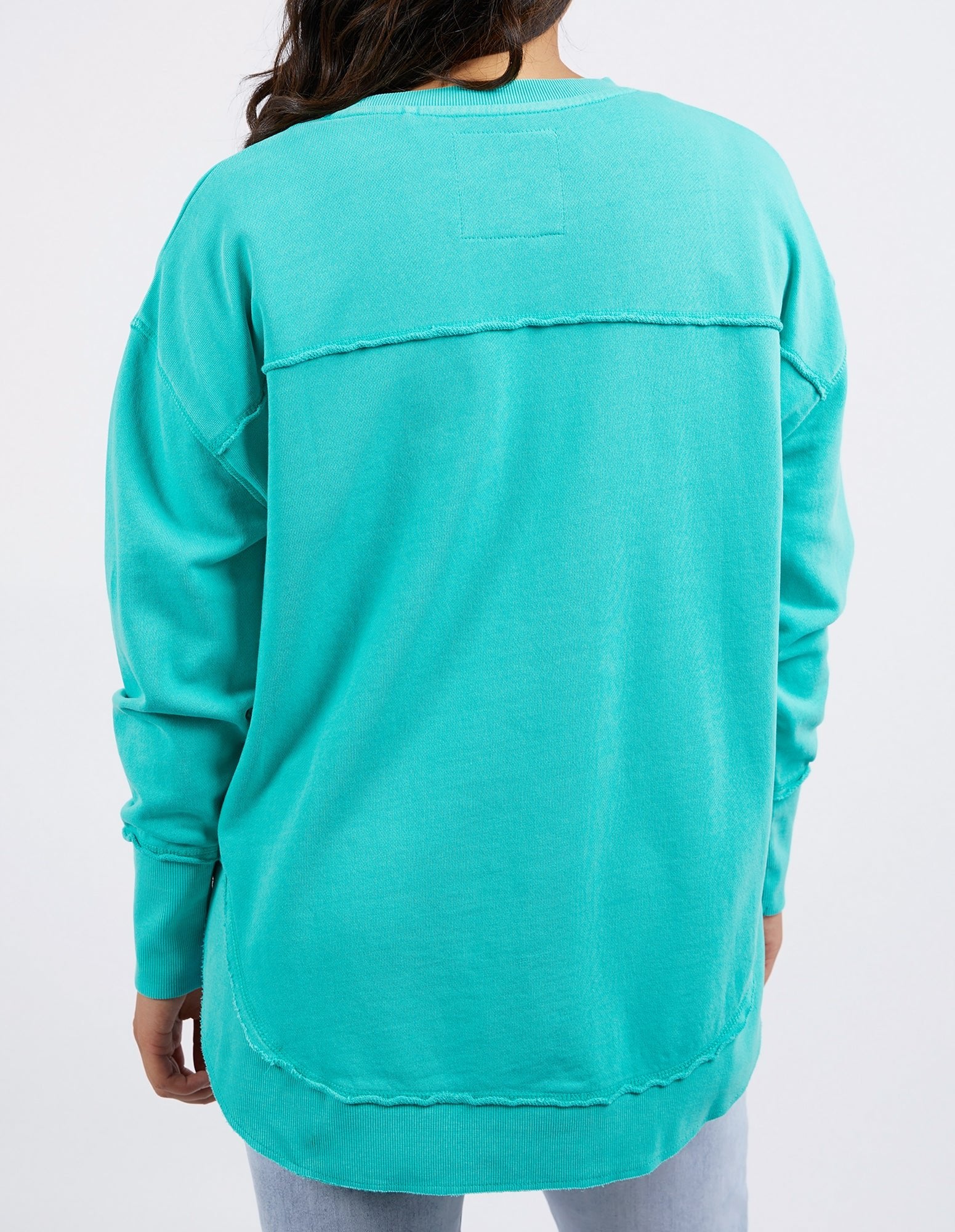 Image of Woman wearing Foxwood Simplified crew in a teal colourway paired with denim jeans on a plain background 
