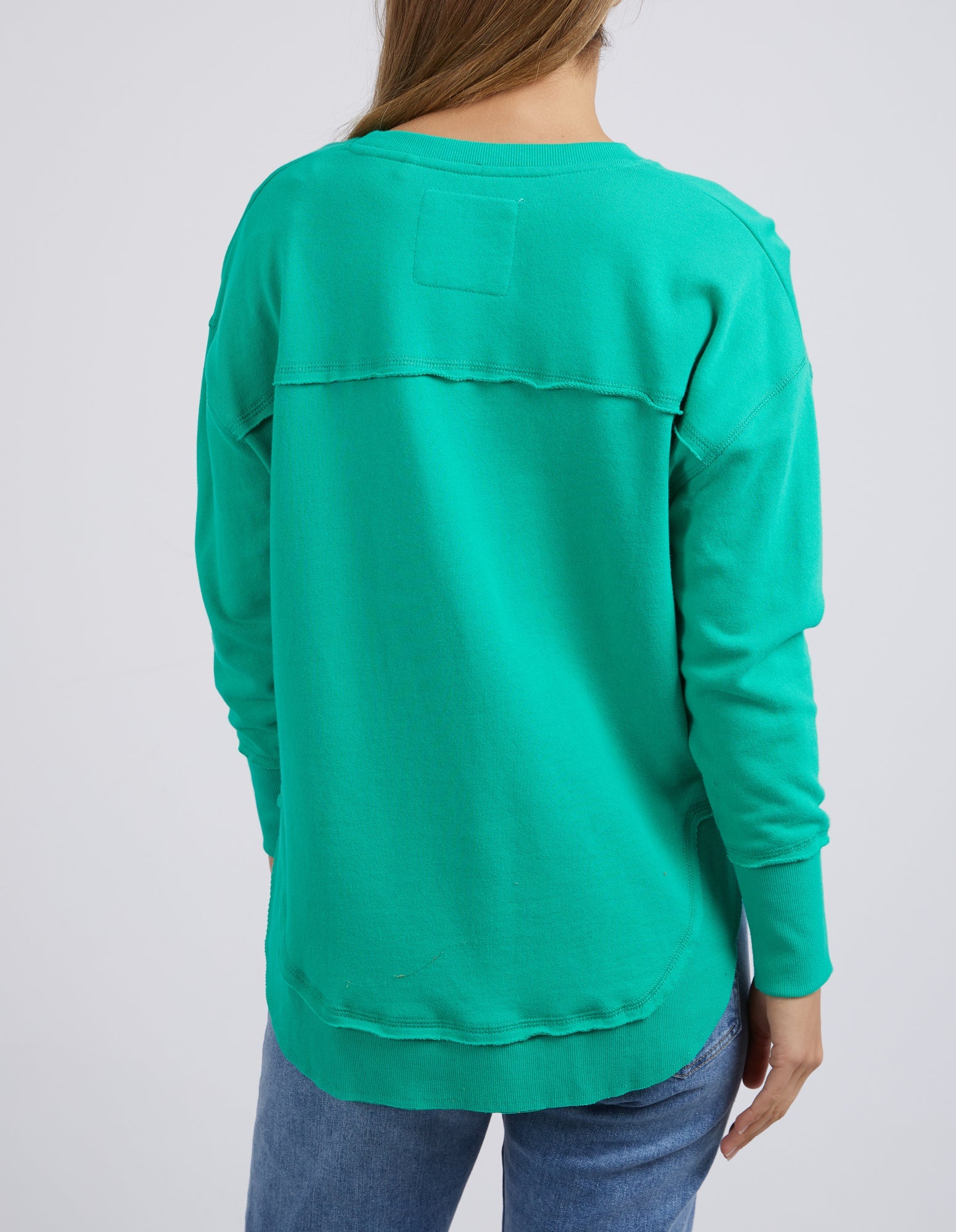 Image of Woman wearing Foxwood Simplified Metallic Crew in Bright Green paired with denim jeans on plain background 