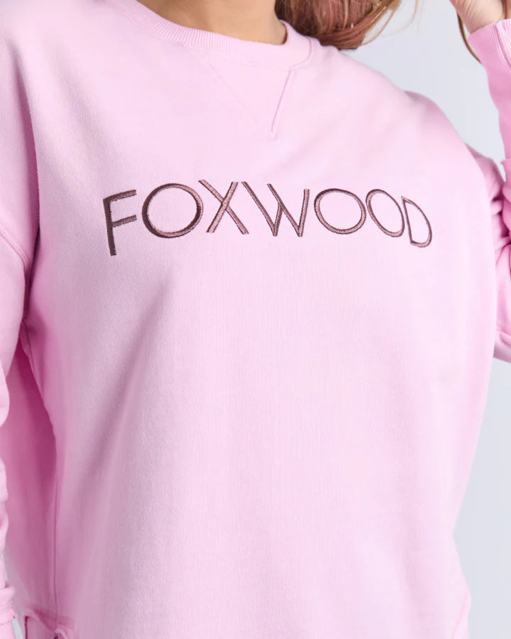 Image of Pink sweatshirt with 'FOXWOOD' text on the back against a light gray background