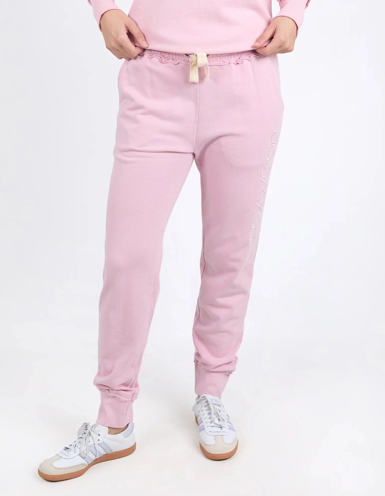 A woman wearing Foxwood light pink jogger sweatpants with a lace-up elastic waistband and white sneakers, shown from the waist down against a plain white studio background.