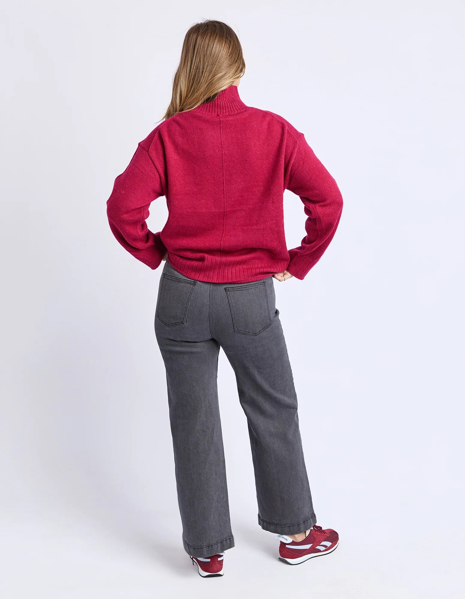 Image of Woman wearing a Foxwood red sweater and gray pants on a white background