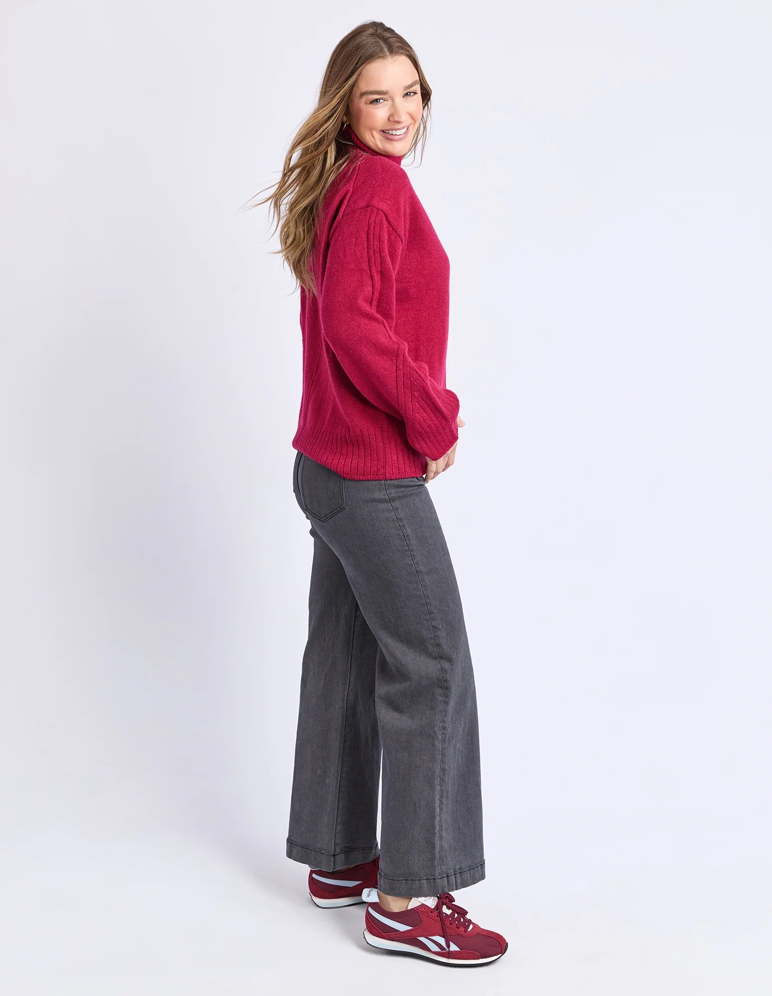 Image of Woman wearing a Foxwood red sweater and gray pants on a white background