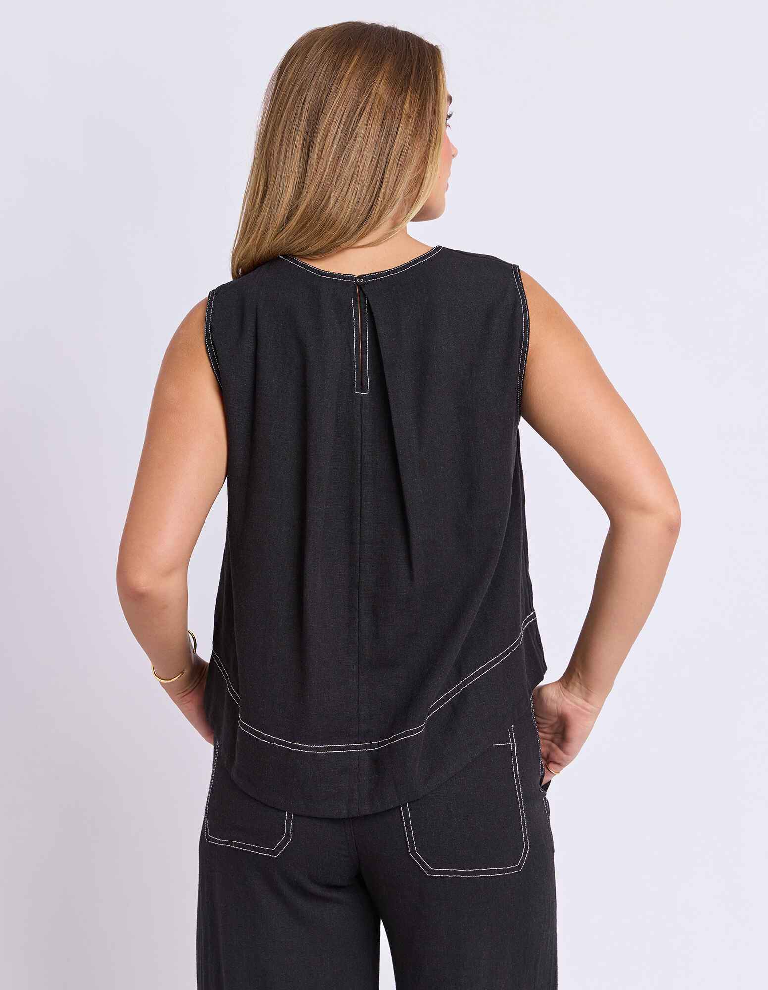 Image of Woman wearing a Foxwood black sleeveless top and pants on a light gray background