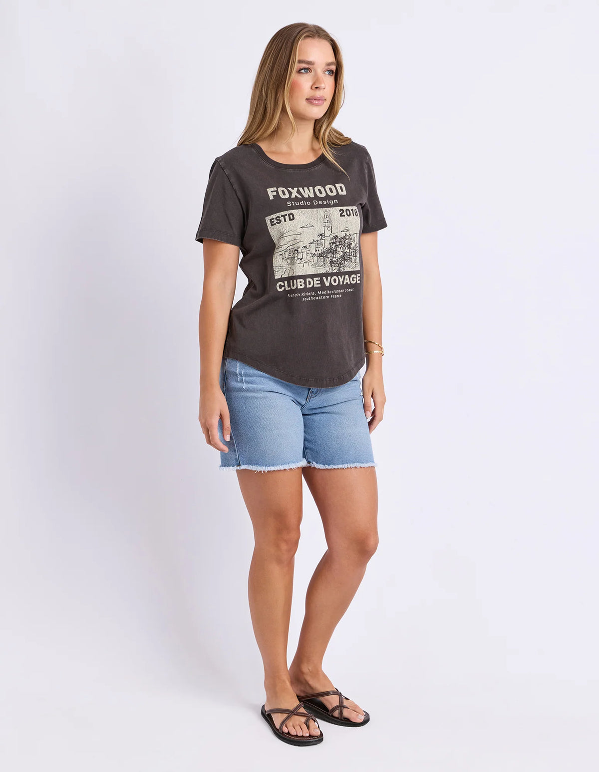 Woman wearing a Foxwood black printed graphic t shirt paired with denim jeans on a plain background