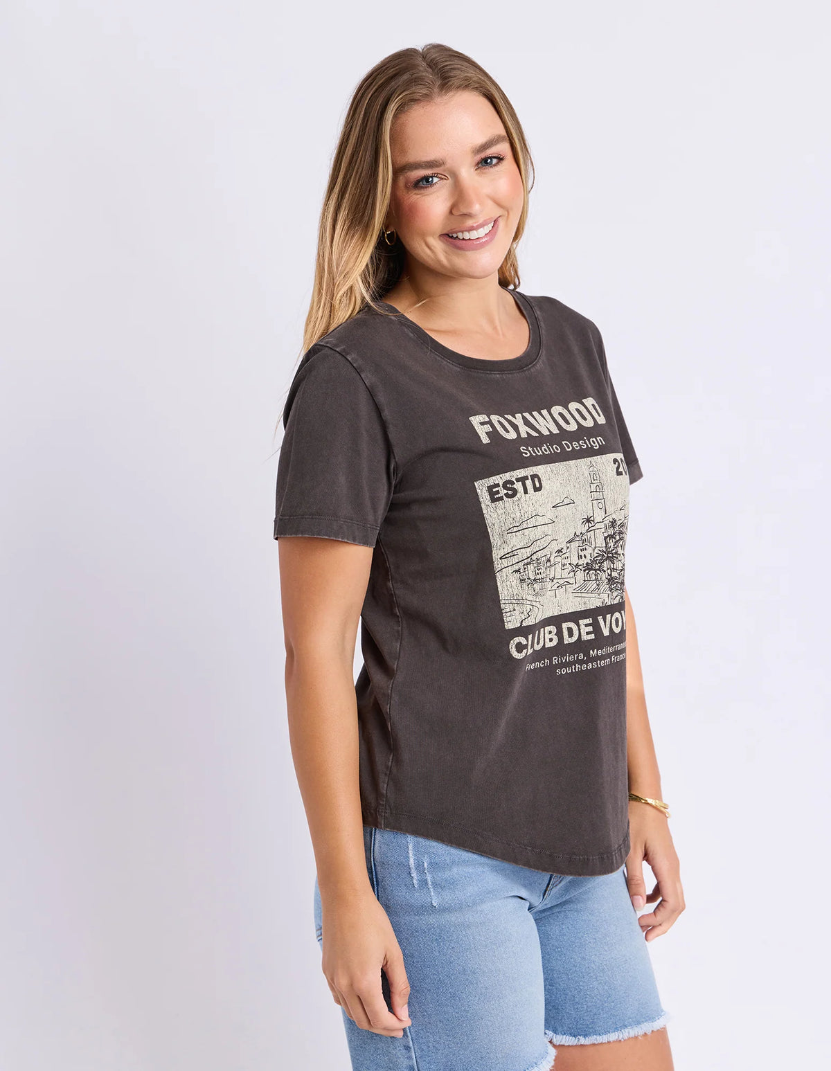 Woman wearing a Foxwood black printed graphic t shirt paired with denim jeans on a plain background