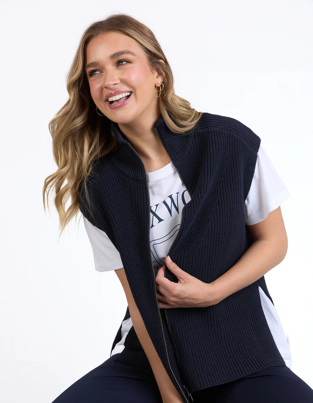 Woman wearing a Foxwood navy vest over a white t-shirt with text on a plain background