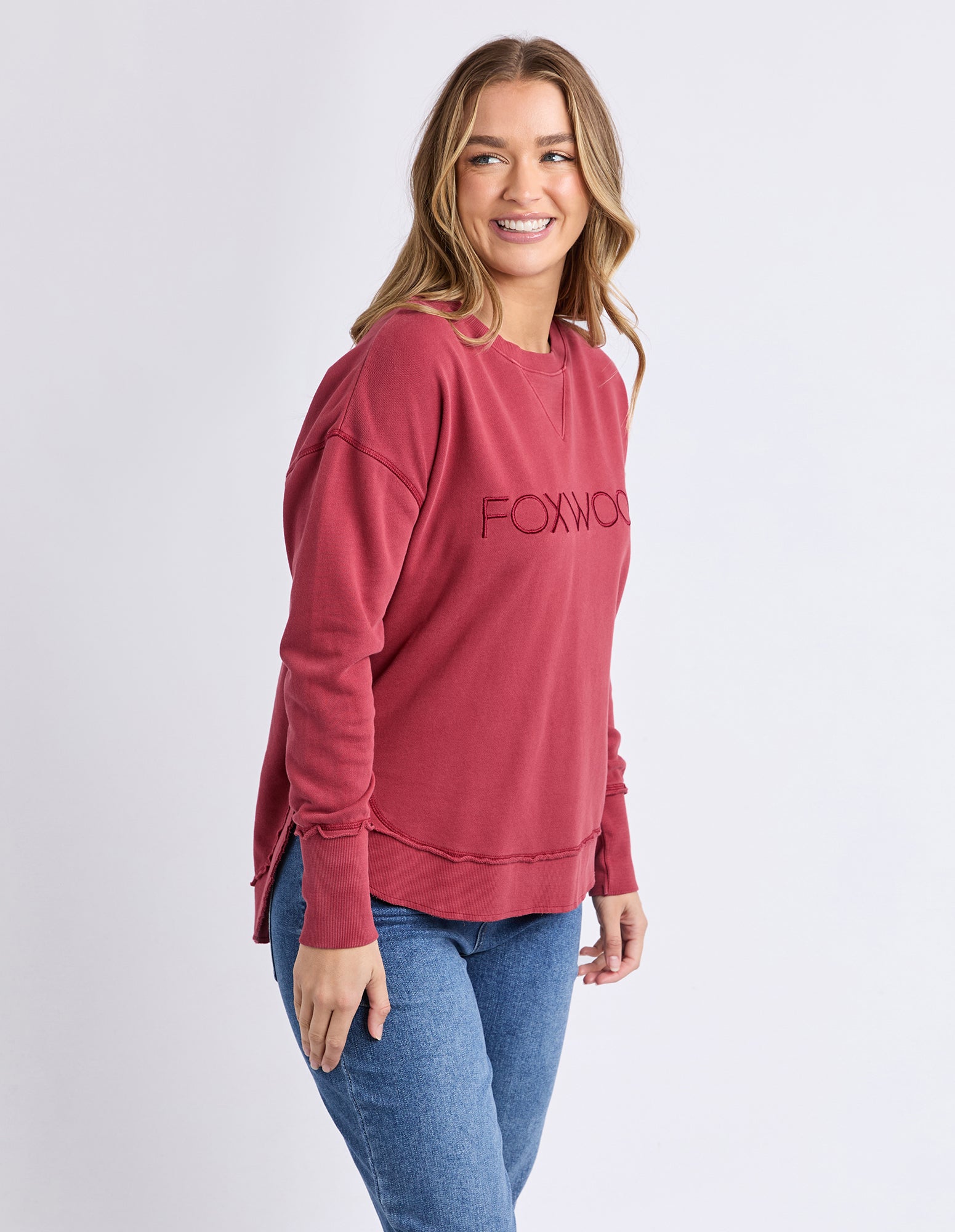 Woman wearing a red jumper with 'Foxwood' logo on a white background