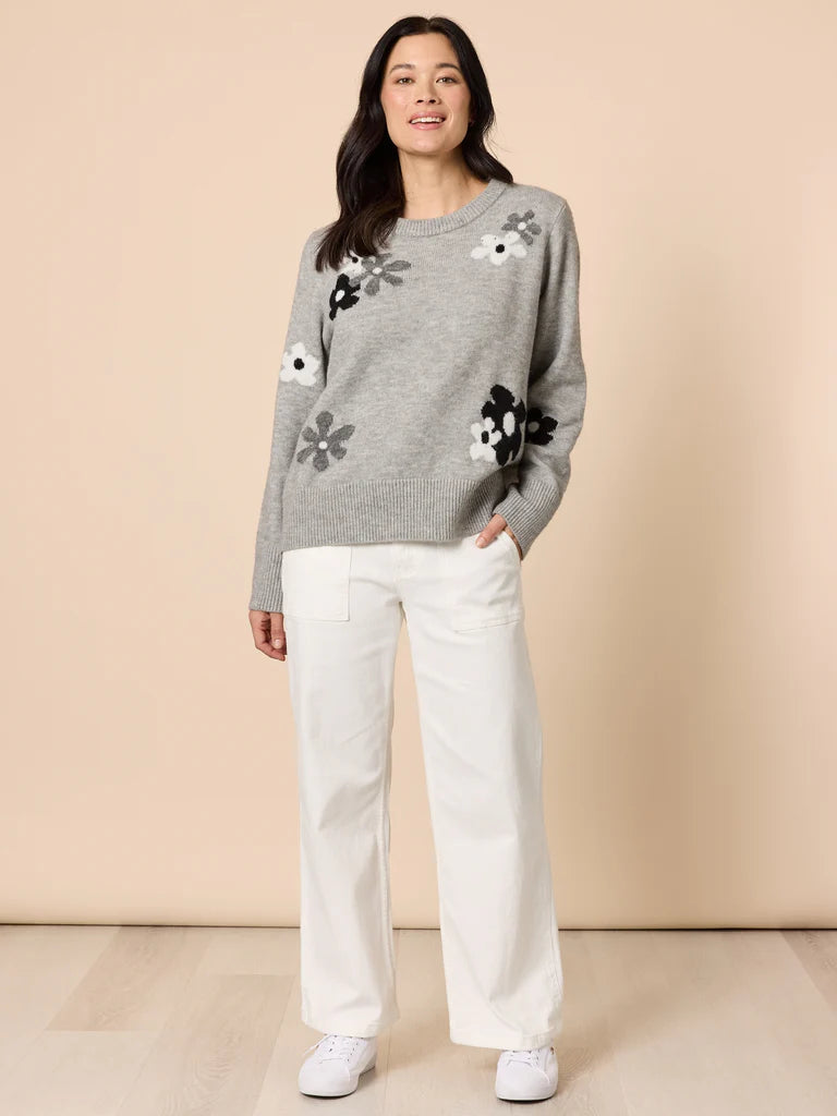 Collection of Woman wearing a Gordon Smith grey sweater with floral patterns and white pants on a beige background in a gallery layout