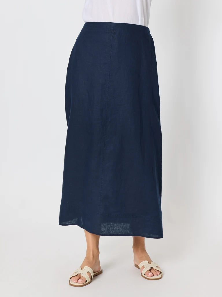Image of Gordon Smith navy blue linen midi skirt worn by a model, paired with a white top and beige slide sandals, photographed against a light gray studio background.