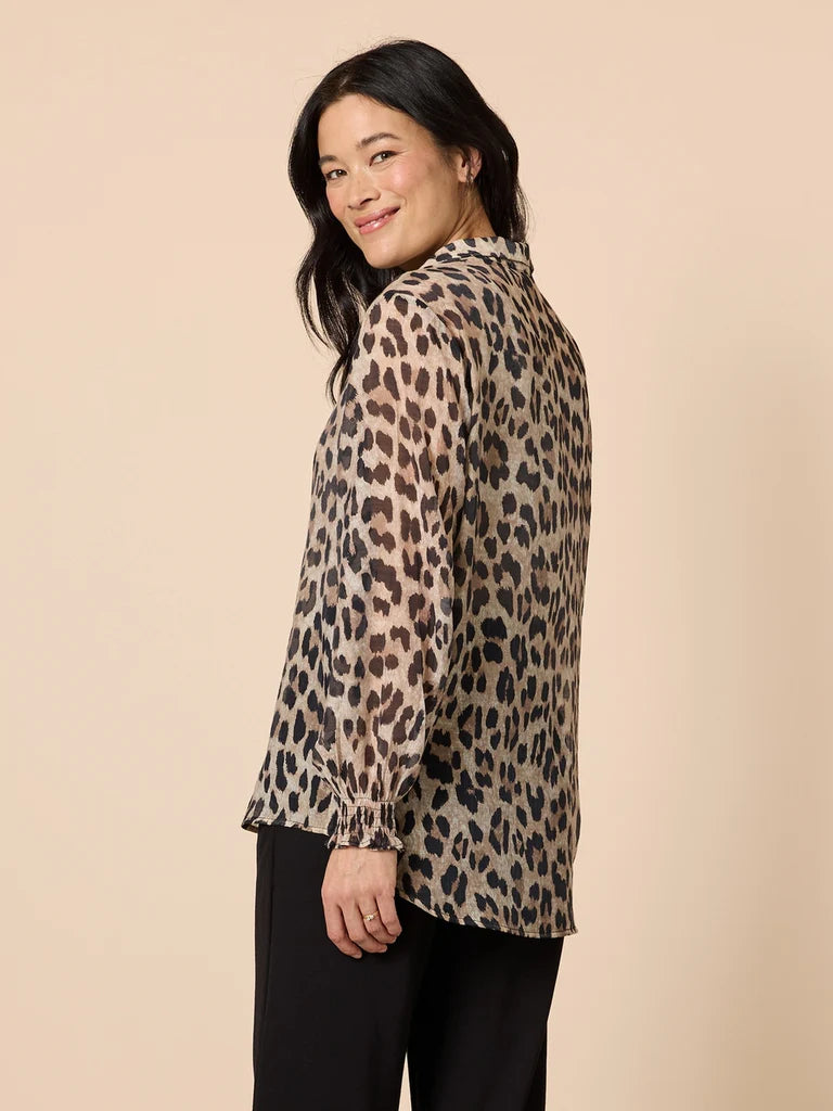 Woman wearing a Gordon Smith leopard print blouse against a beige background