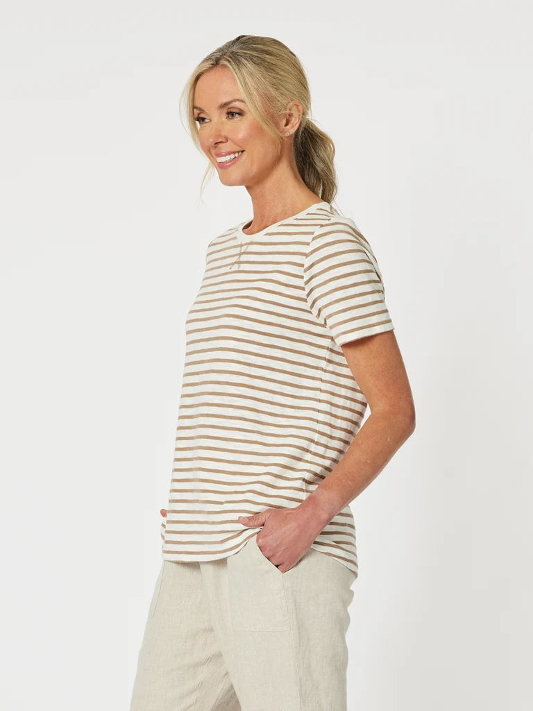Image of A woman wearing a Gordon Smith short-sleeve crewneck t-shirt with thin beige and white horizontal stripes, paired with light beige pants, photographed against a solid white studio background.
