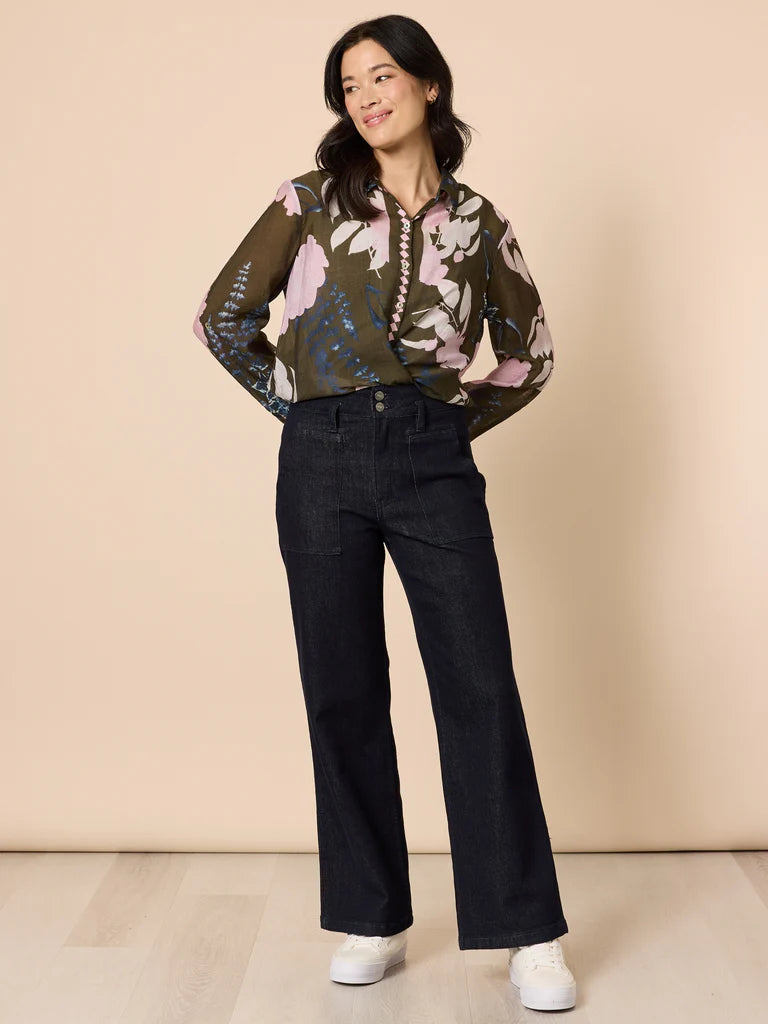 Woman wearing a Gordon Smith floral blouse and black pants against a beige background